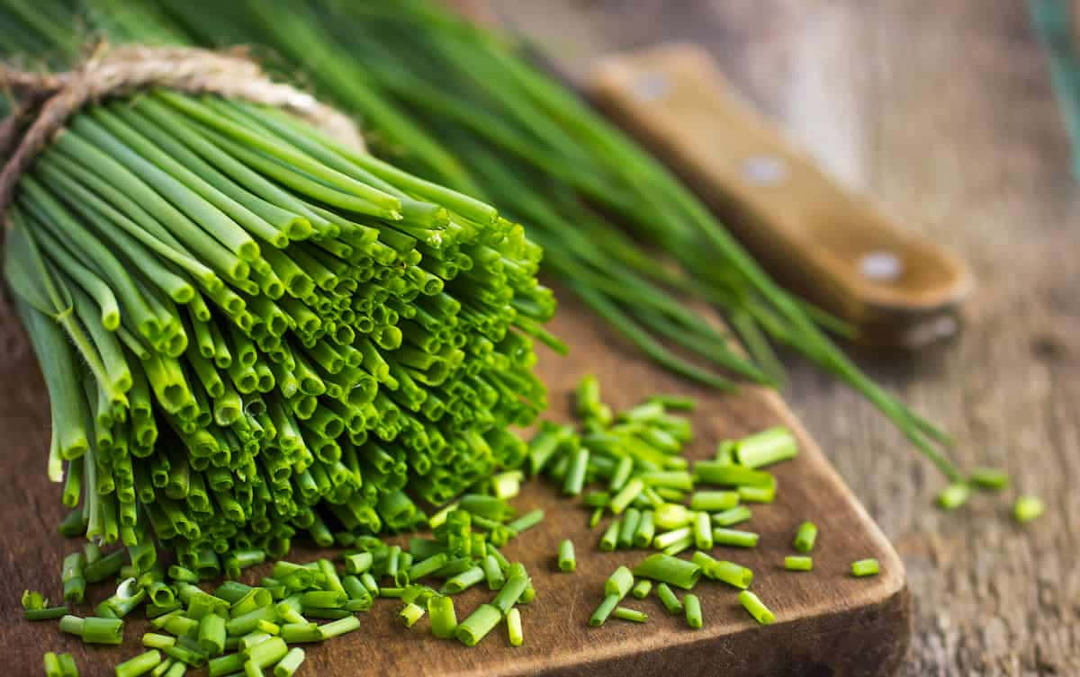 Food Photography 桌布 壁紙 — 新鮮翠綠的韭菜用麻繩捆紮，並在質樸的木砧板上切碎。