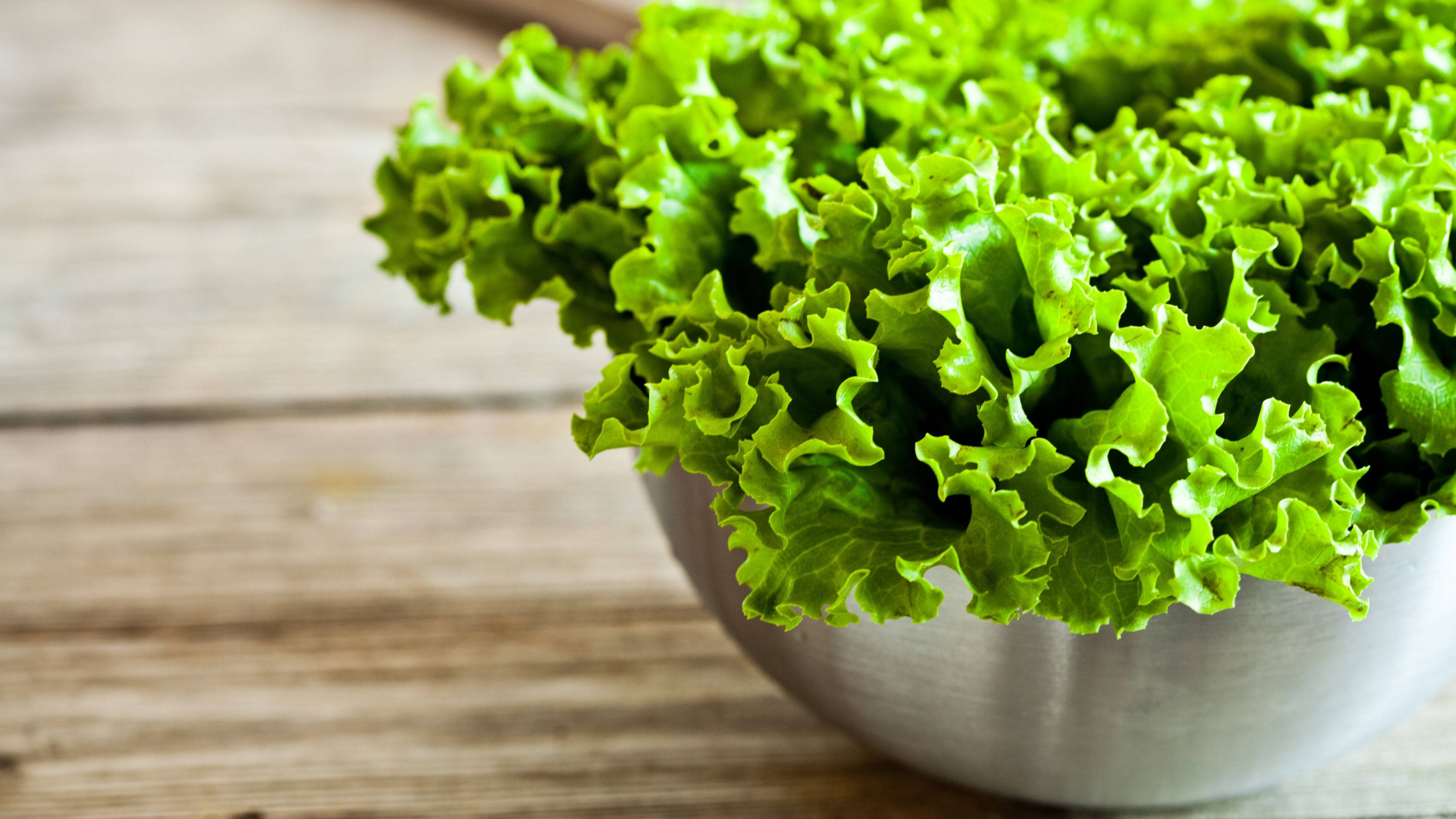 Vegetables 桌布 壁紙 — 新鮮脆嫩的綠色生菜葉從白色碗中溢出，置於鄉村風格的木質表面上。
