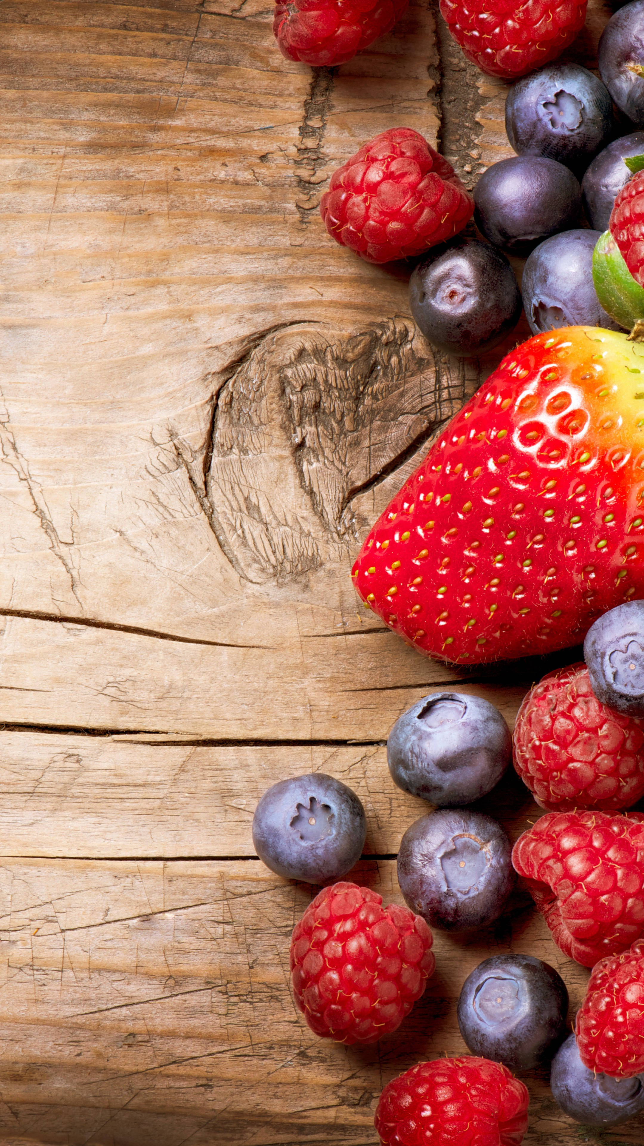 Fruit 桌布 壁紙 — 新鮮草莓、覆盆子和藍莓散落在質樸的木質表面上。