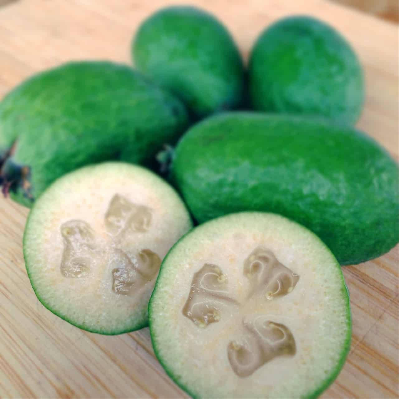 Fruit 桌布 壁紙 — 新鮮菲油果切開，露出多汁半透明種子，放在木砧板上。