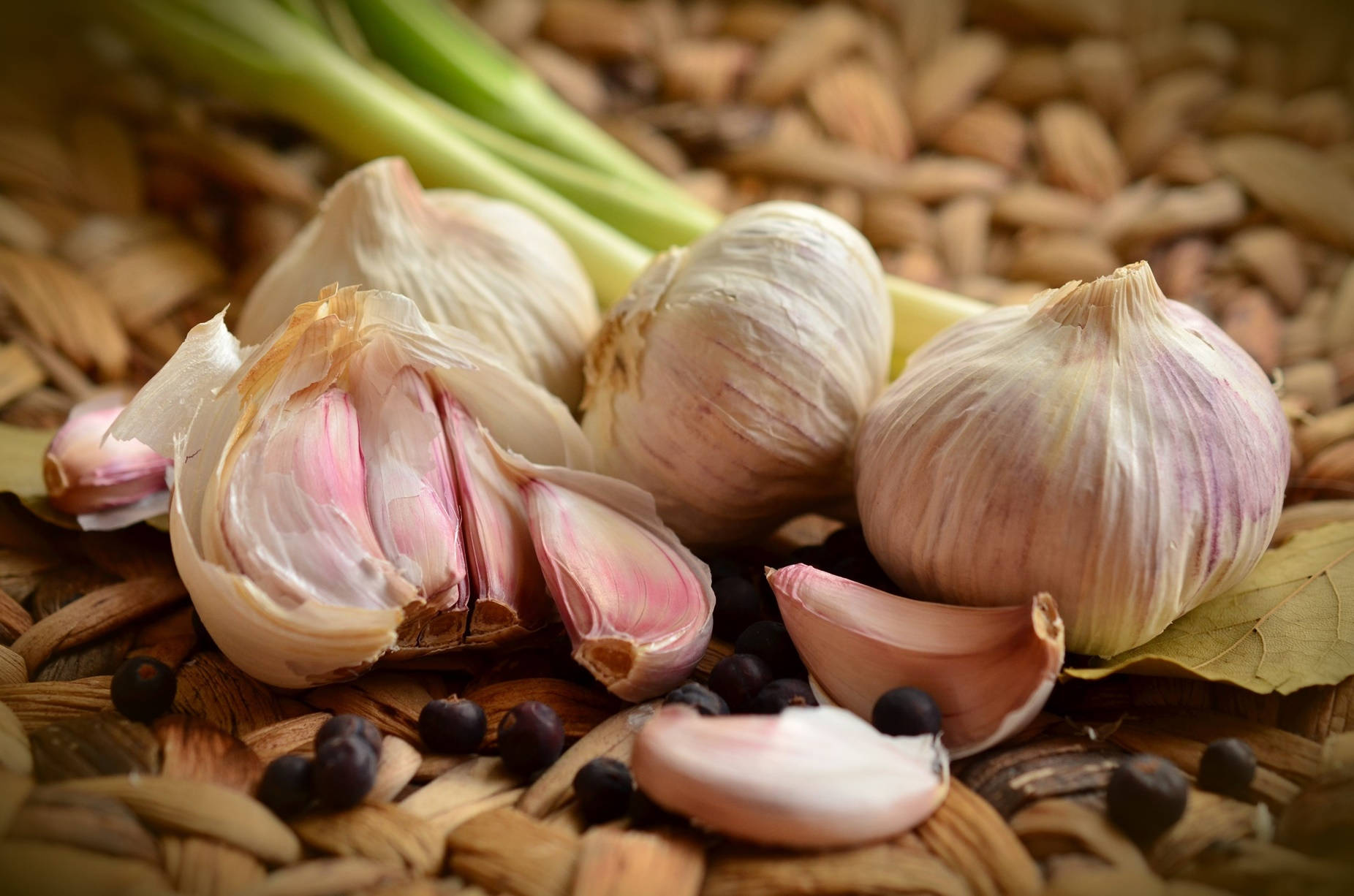 Garlic 桌布 壁紙 — 新鮮蒜頭和蒜瓣連同胡椒粒和青蔥放在編織竹蓆上。