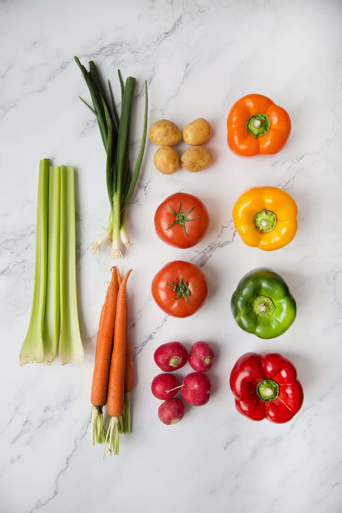 pepper 桌布 壁紙 — 新鮮蔬菜包括紅蘿蔔、芹菜、小蘿蔔和甜椒整齊地排列在白色大理石表面上。