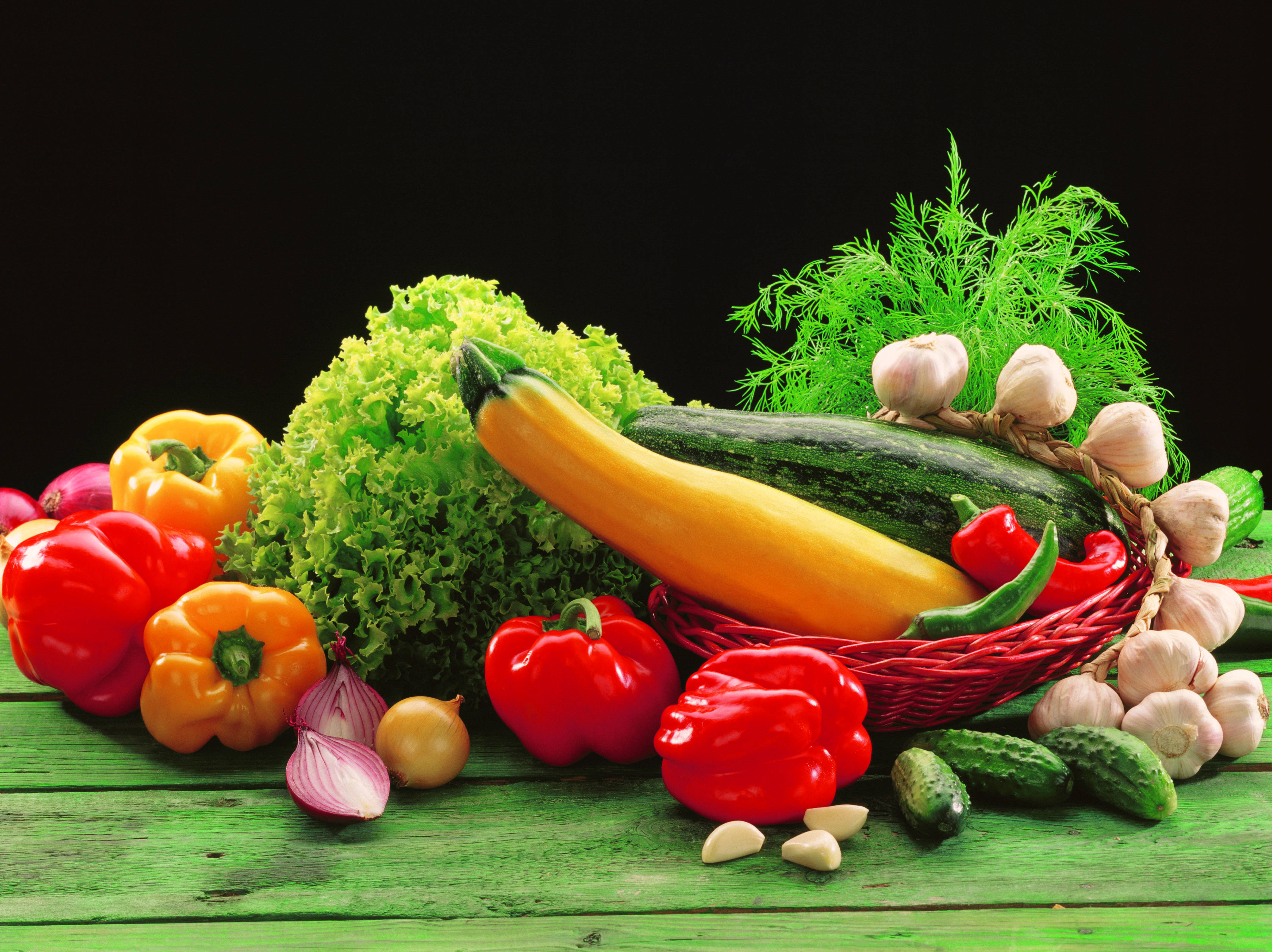 Vegetable 桌布 壁紙 — 新鮮蔬菜如甜椒、櫛瓜和大蒜的鮮豔排列，置於經風化的綠色木質表面上，背景為黑色。