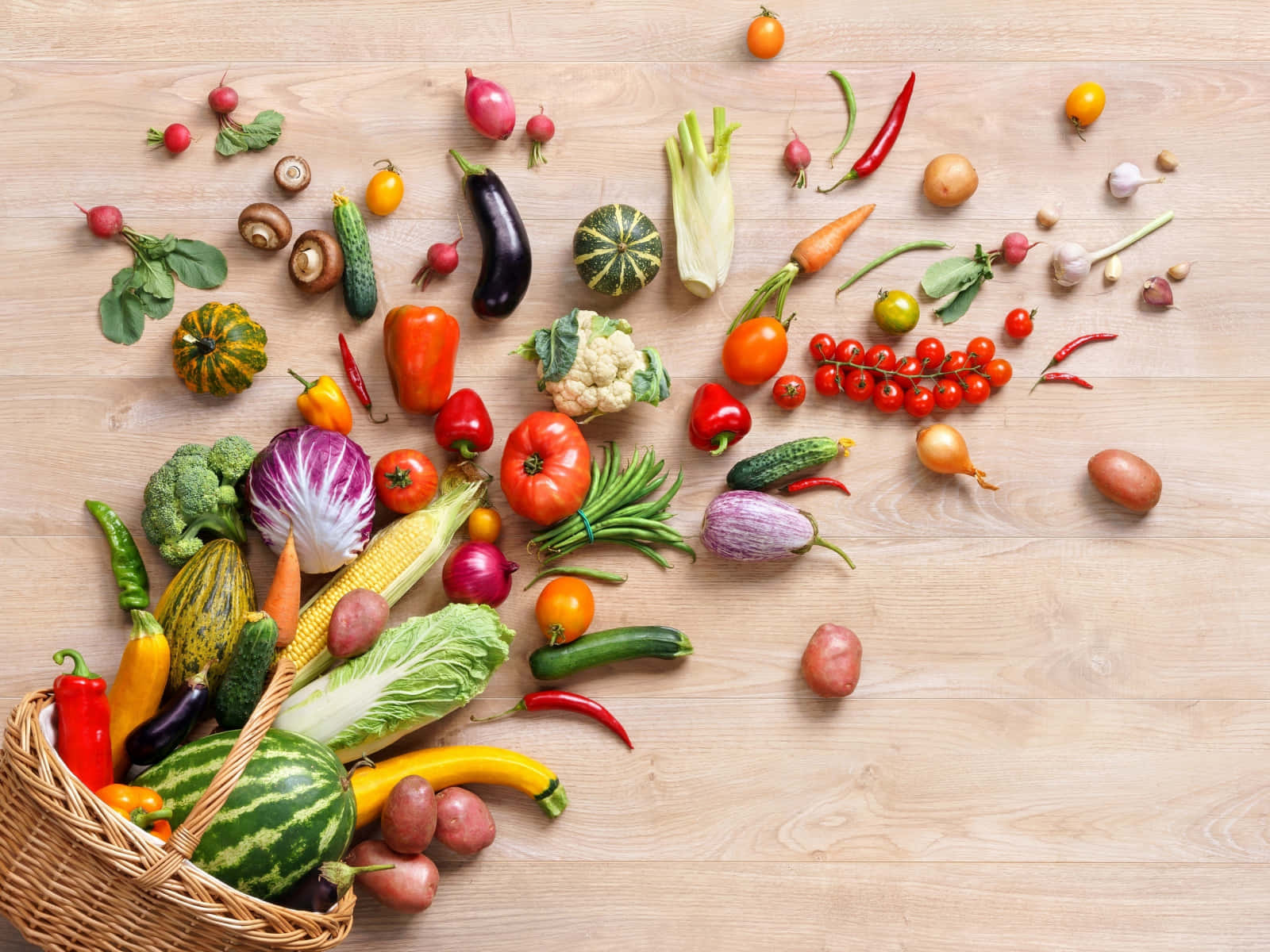 Healthy Food 桌布 壁紙 — 新鮮蔬菜的繽紛組合從柳條籃中溢出，散落在淺色木質表面上。