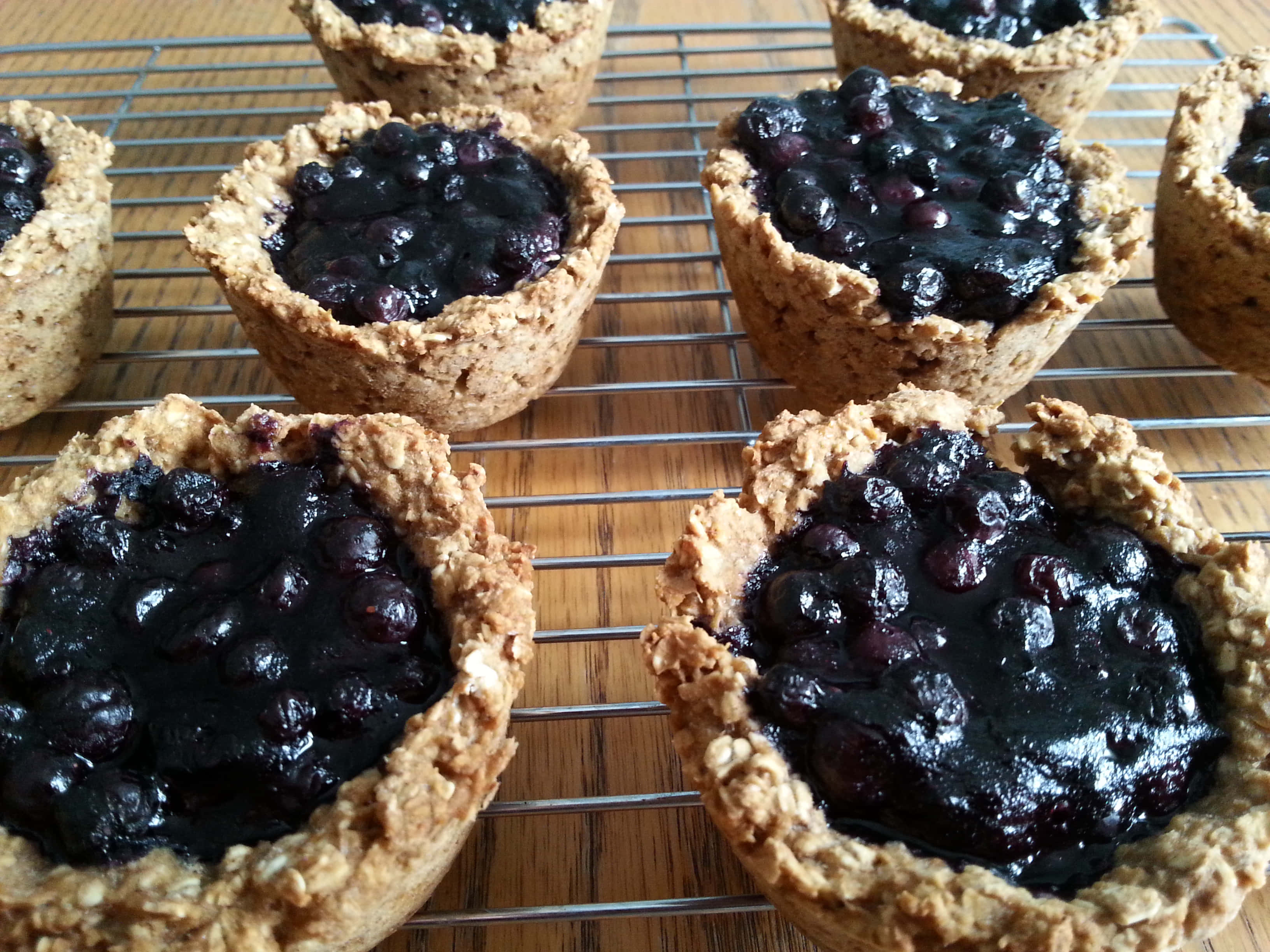 Blueberries Tart 桌布 壁紙 — 新鮮藍莓燕麥塔在竹面上的金屬架上冷卻中。