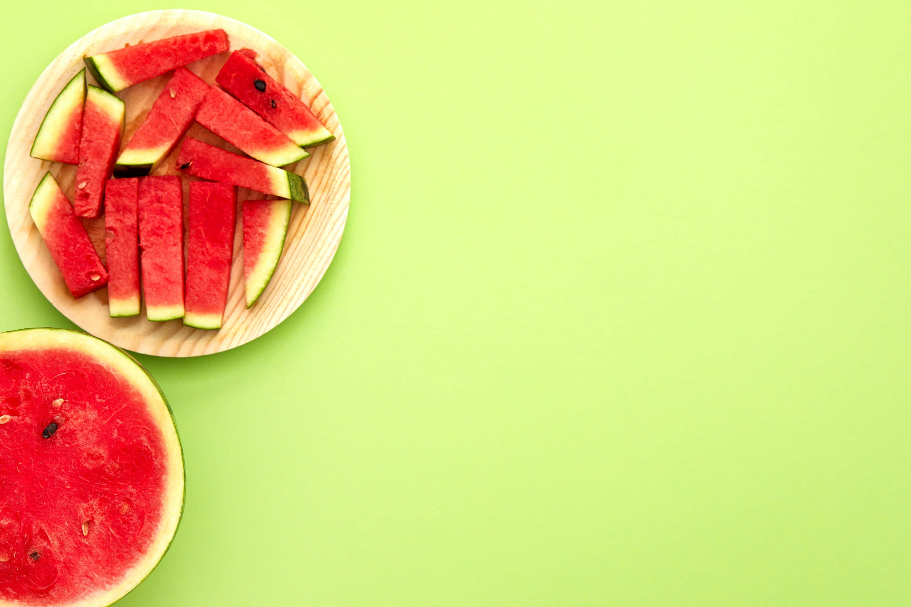 Watermelon 桌布 壁紙 — 新鮮西瓜片擺放在木盤上，背景為鮮綠色。