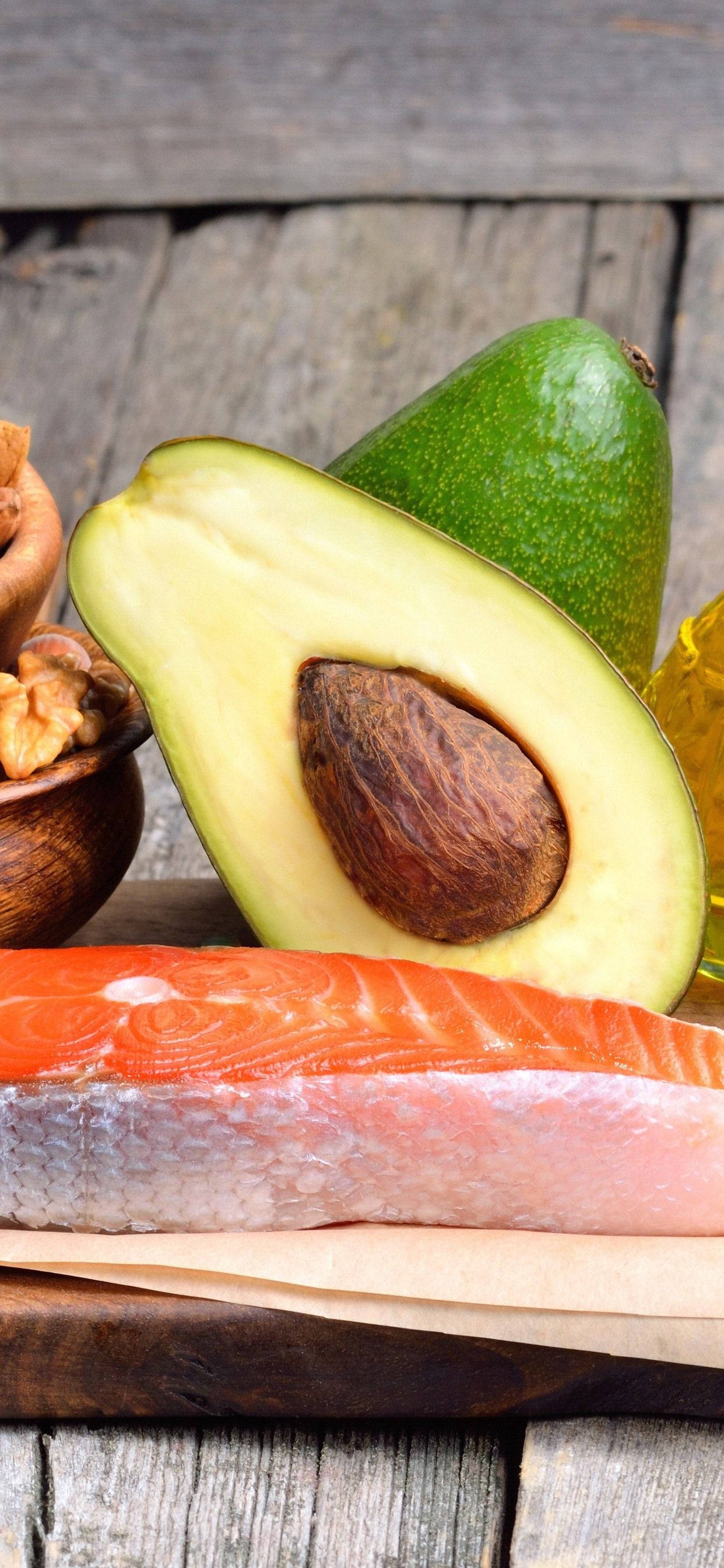Fruits 桌布 壁紙 — 新鮮酪梨、鮭魚和核桃在溫暖自然光下擺放在鄉村風木質表面上。