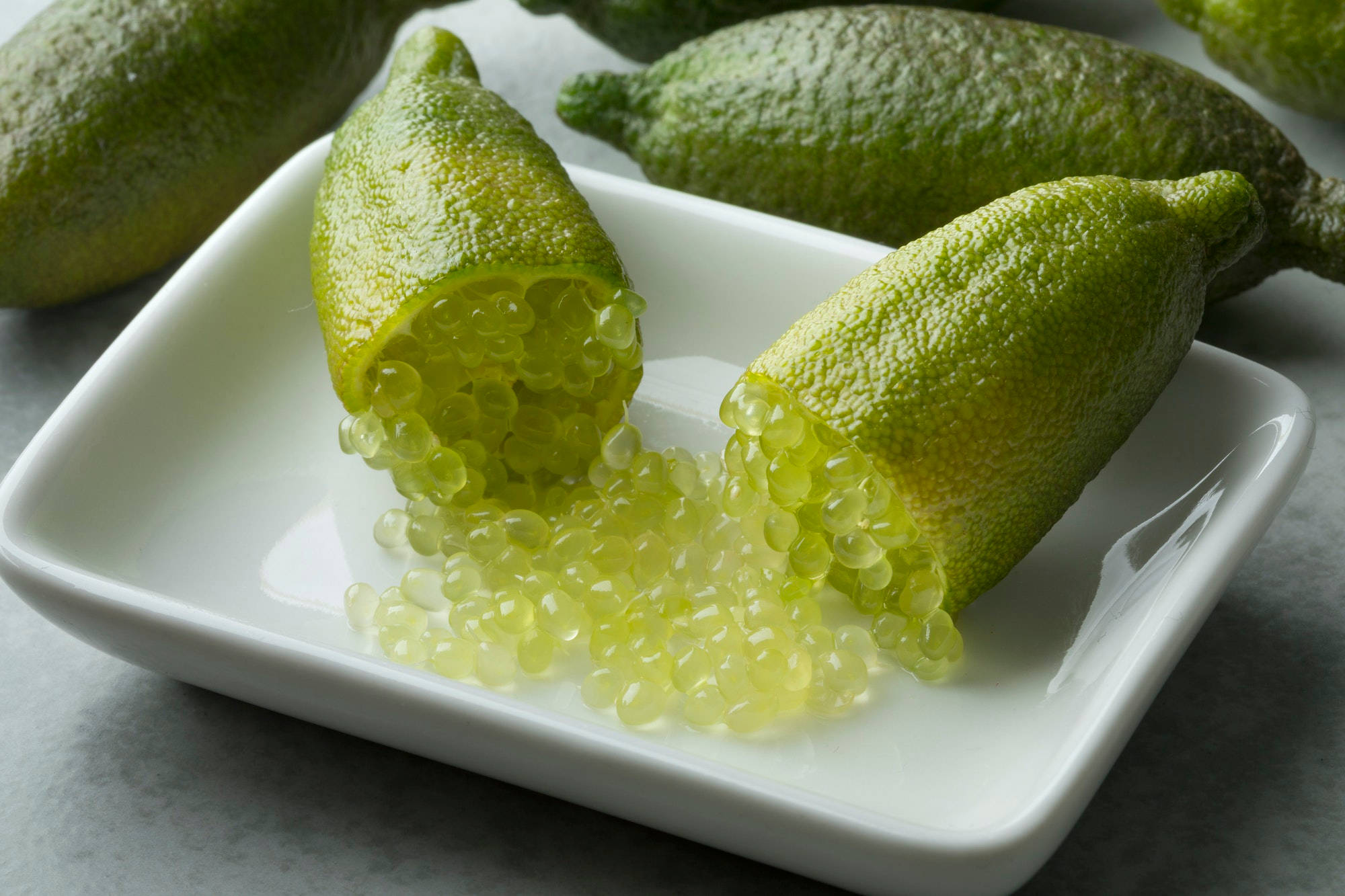 Fruits 桌布 壁紙 — 新鮮金桔切開，露出閃閃發光的半透明種子，灑落在白色陶瓷盤上。