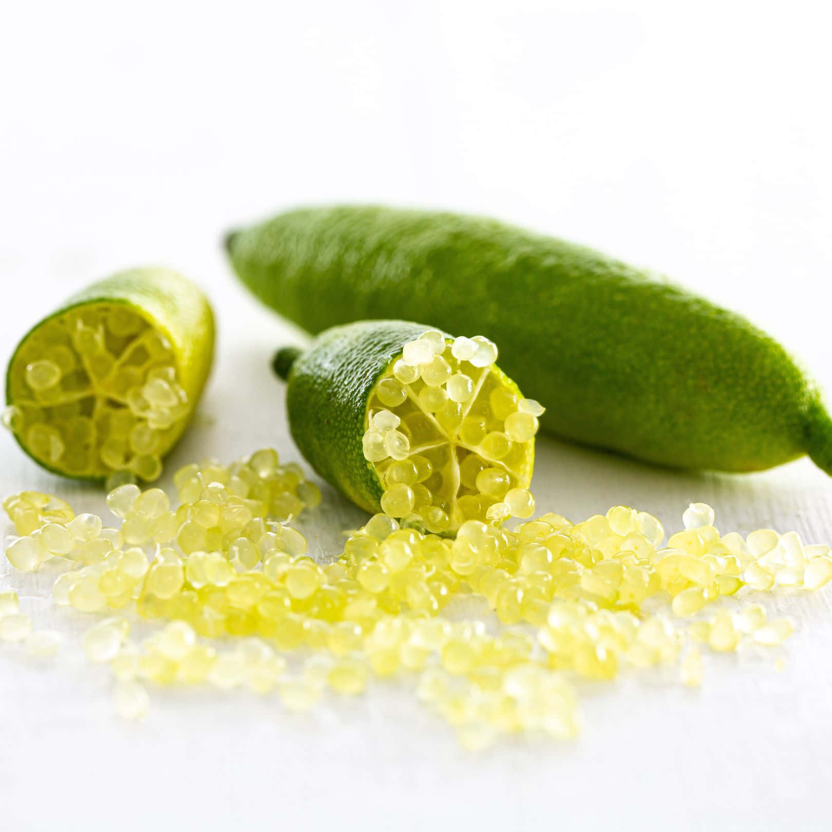 Lime 桌布 壁紙 — 新鮮金桔切開，露出閃閃發光的半透明種子，放在明亮的白色表面上。