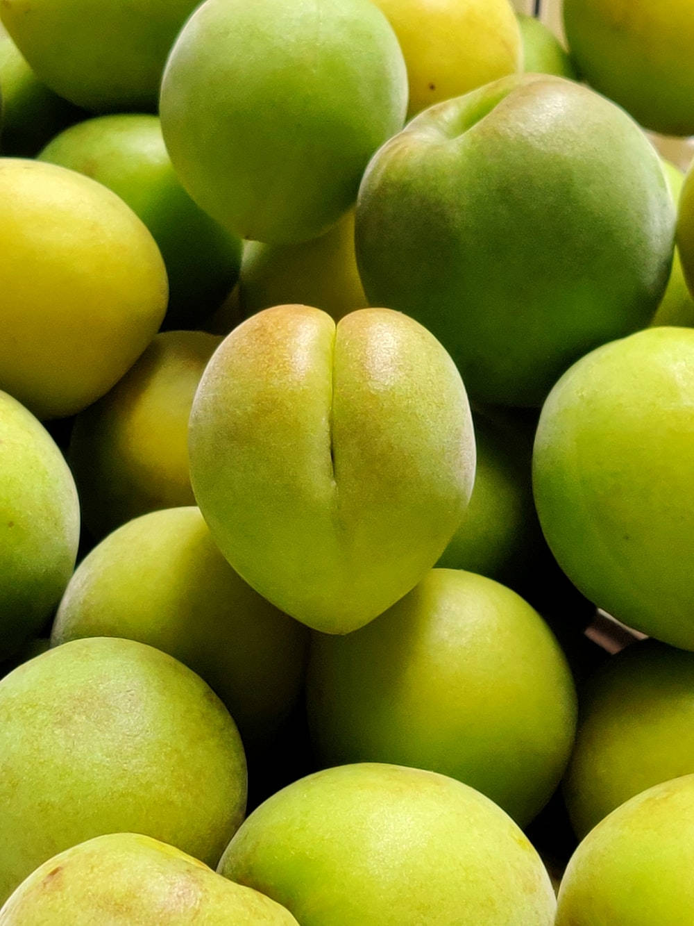 Fruit 桌布 壁紙 — 新鮮青李子堆疊在一起的近距離特寫，表皮光滑，帶有微妙的黃色亮點。