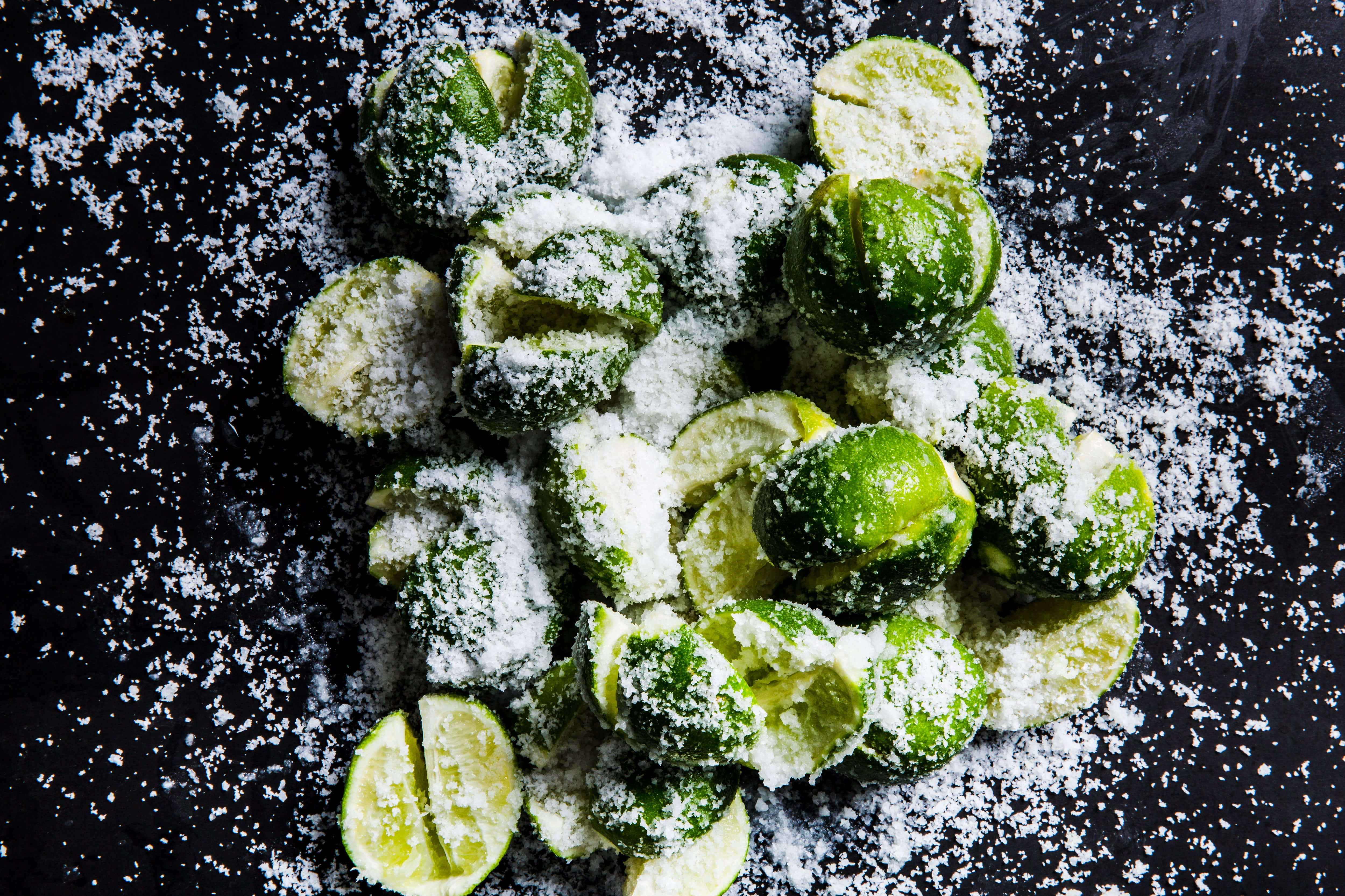 Lime 桌布 壁紙 — 新鮮青檸切片，撒上粗鹽，置於深色紋理表面上。