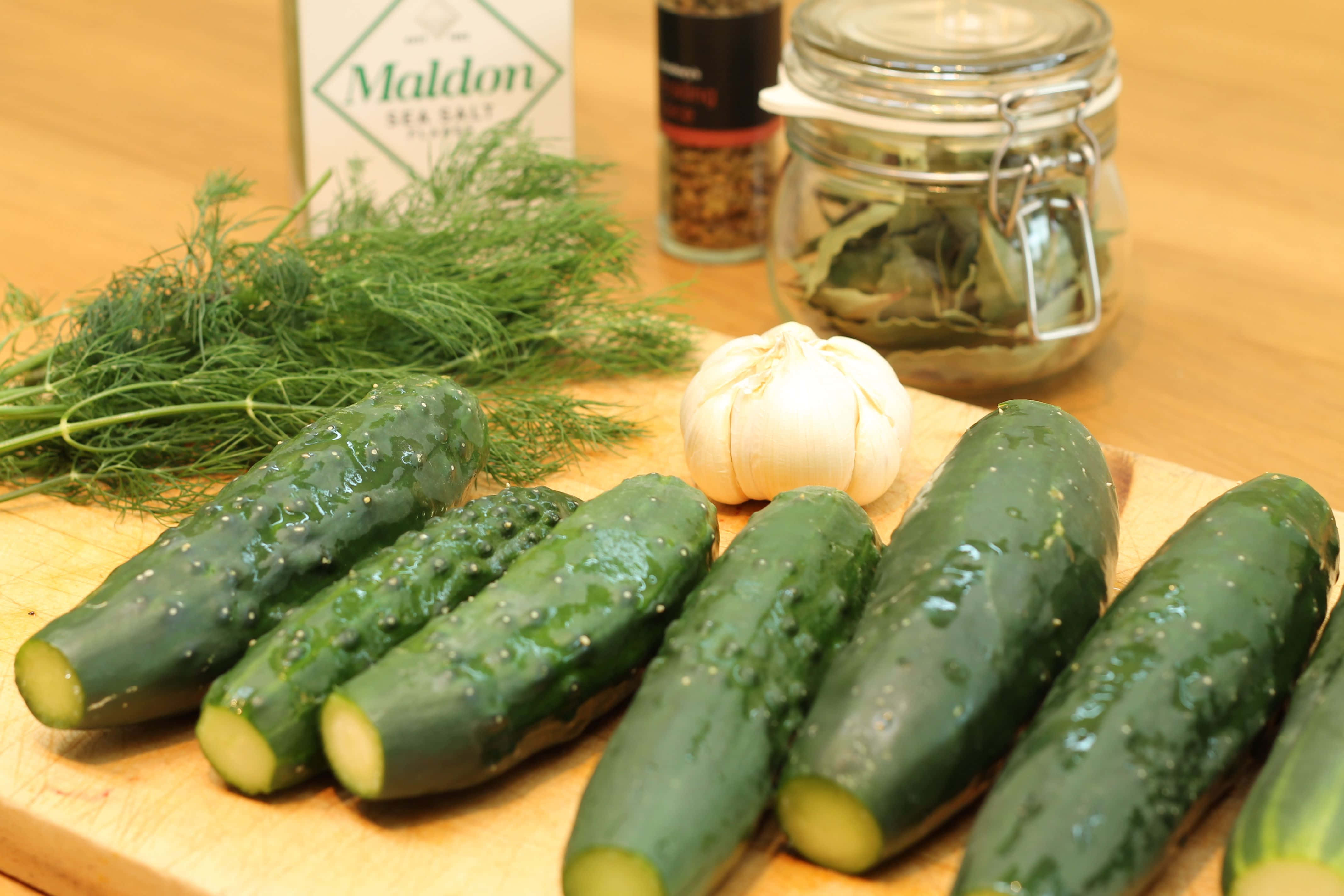 cucumber 桌布 壁紙 — 新鮮青瓜、蒔蘿、大蒜和海鹽排列在木製砧板上，準備醃製。