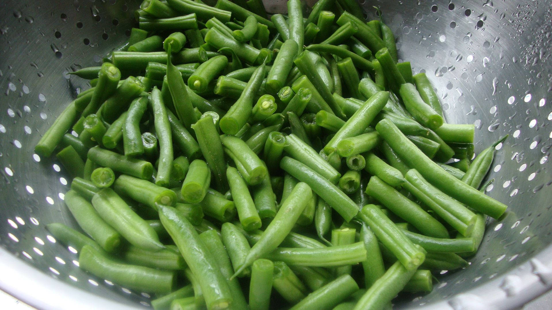 烹飪 桌布 壁紙 — 新鮮青豆在銀色濾器中沖洗後，閃爍著水滴。