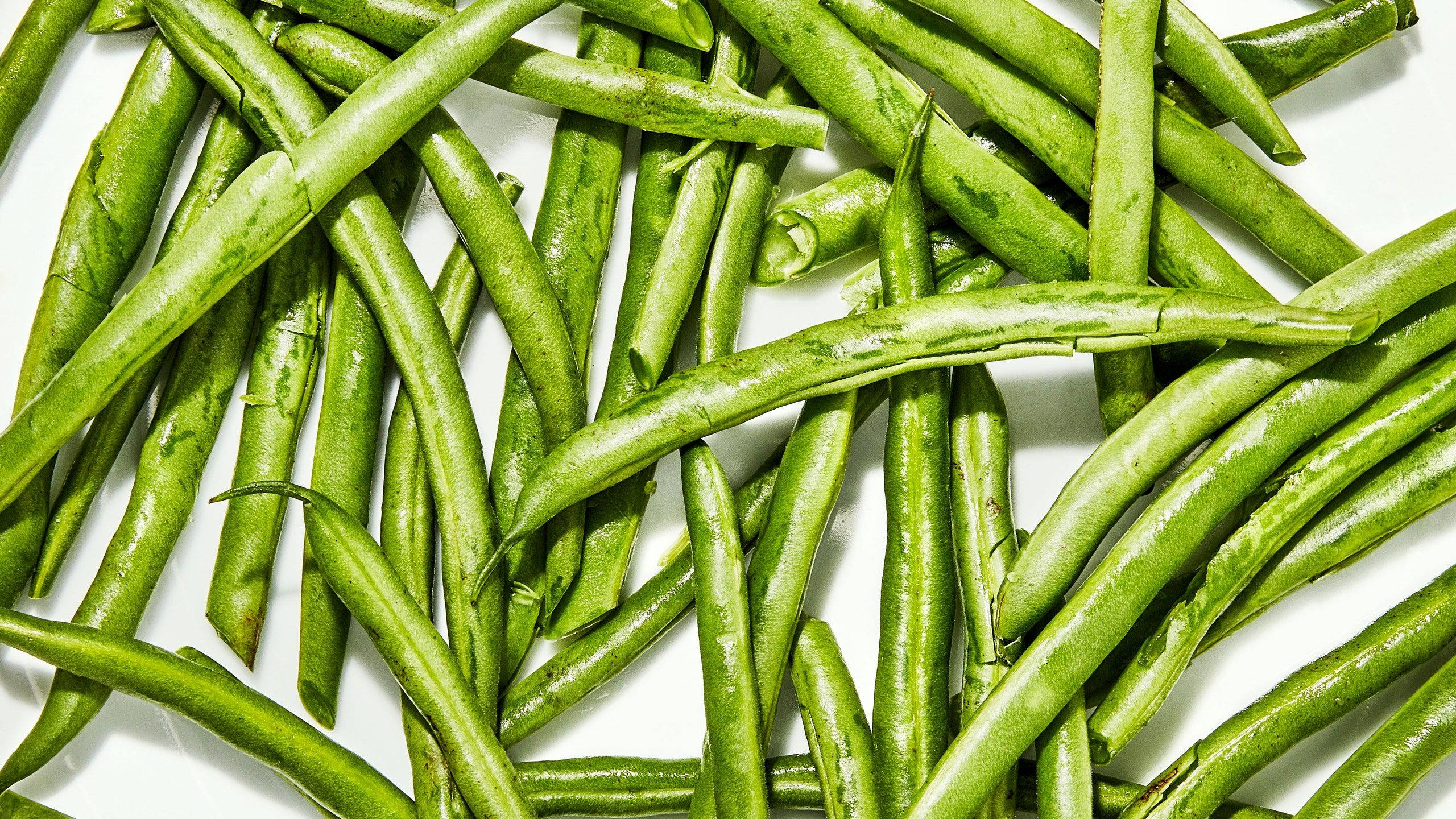 vegan 桌布 壁紙 — 新鮮青豆散落在明亮的白色表面上，具有自然紋理和鮮豔色彩。