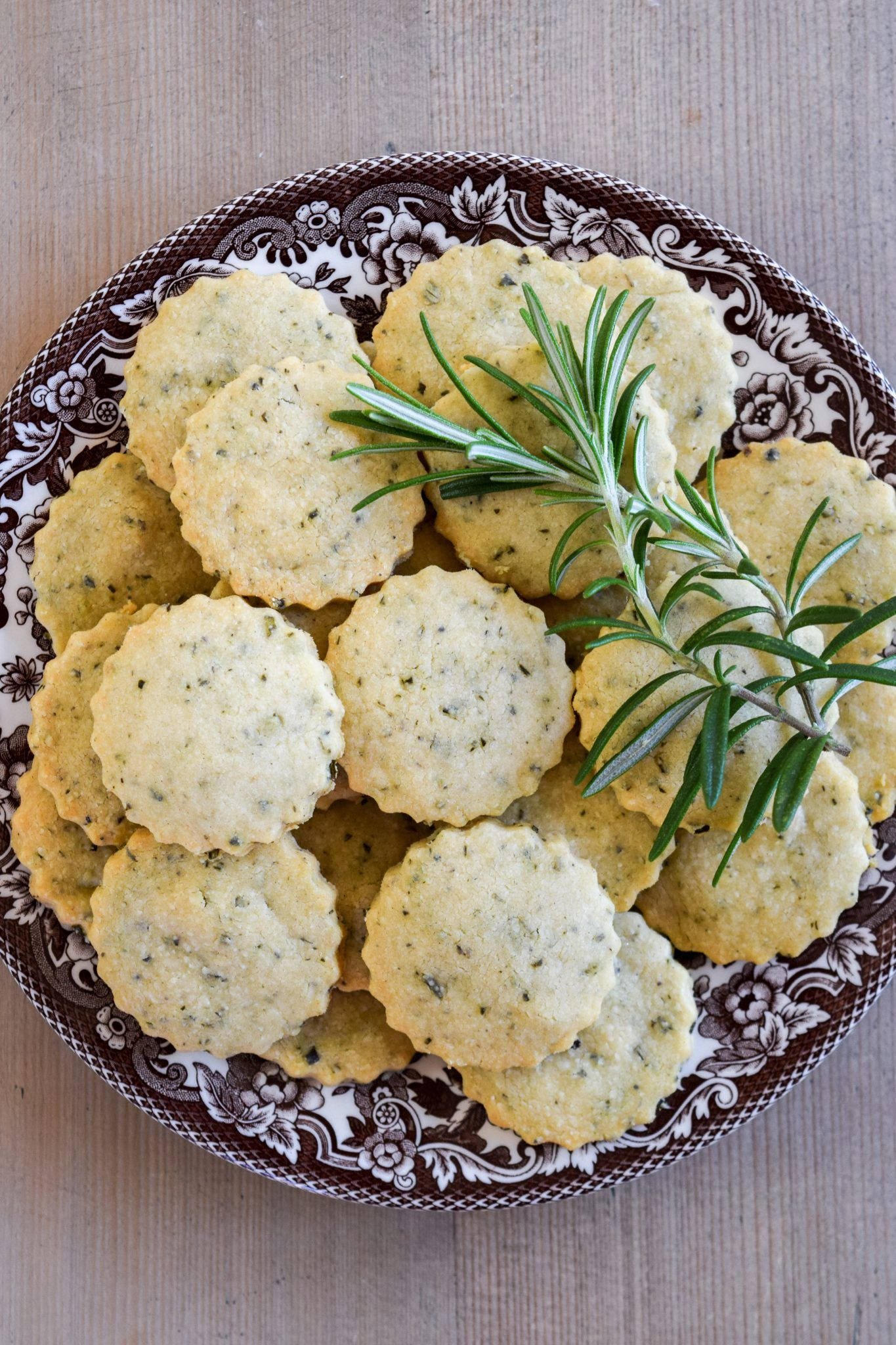 Cookies 桌布 壁紙 — 新鮮香草餅乾堆放在有圖案的盤子上，用一枝迷迭香裝飾，放在木質表面上。
