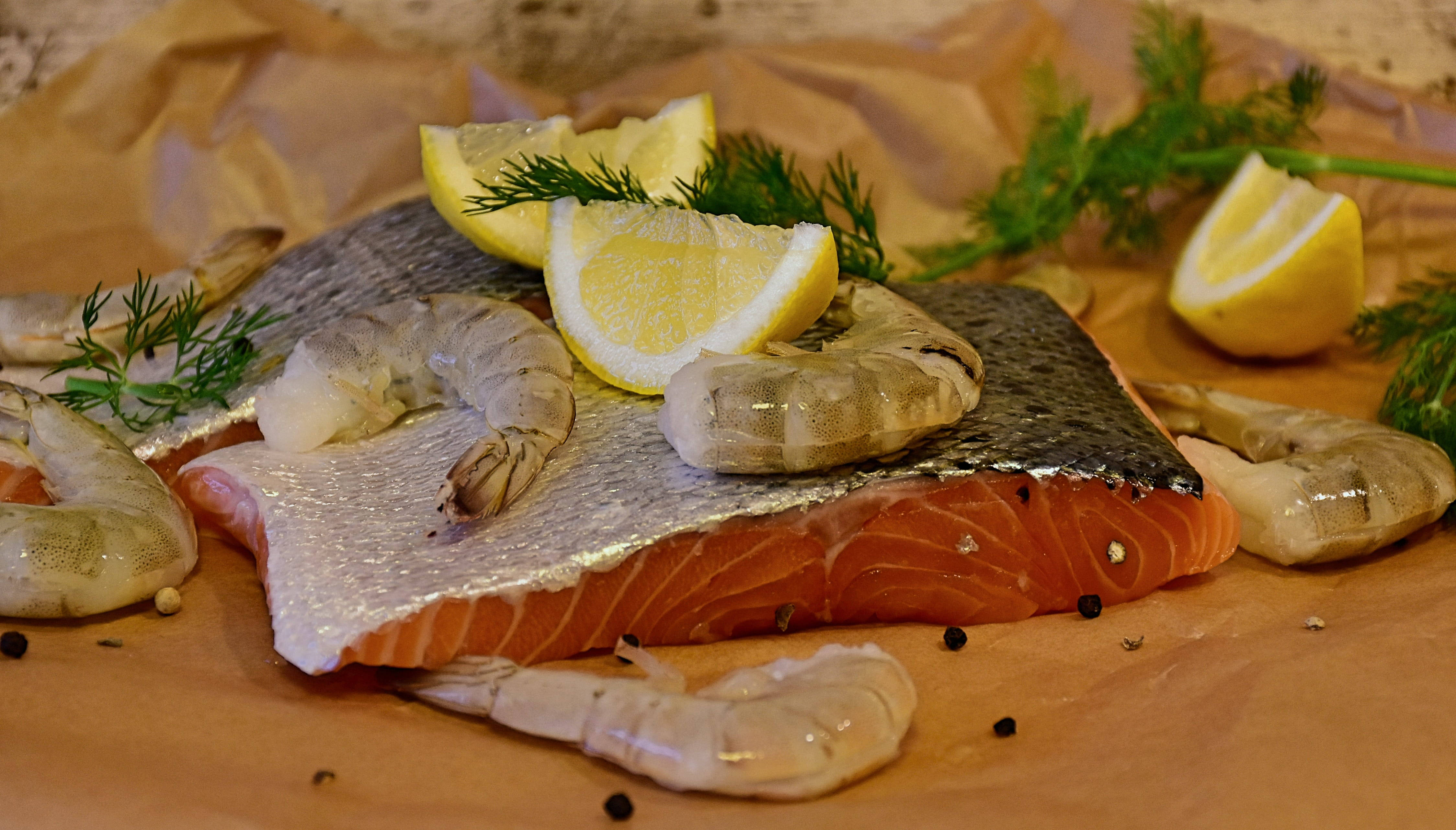 魚 桌布 壁紙 — 新鮮鮭魚菲力搭配蝦仁、檸檬片和蒔蘿，放在皺巴巴的烘焙紙上。