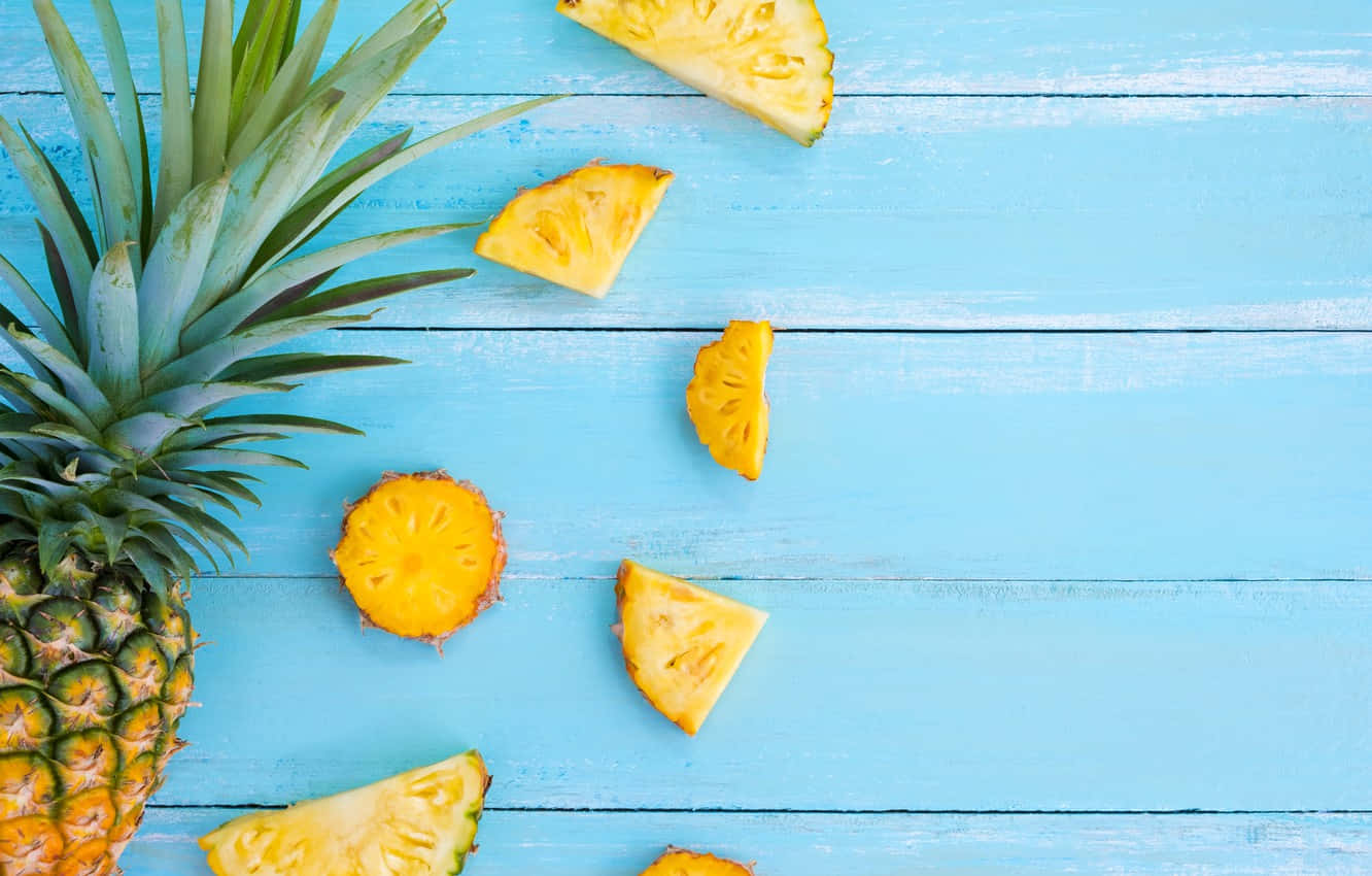 Pineapple Desktop 桌布 壁紙 — 新鮮鳳梨片和冠部散落在亮藍色木質表面上。