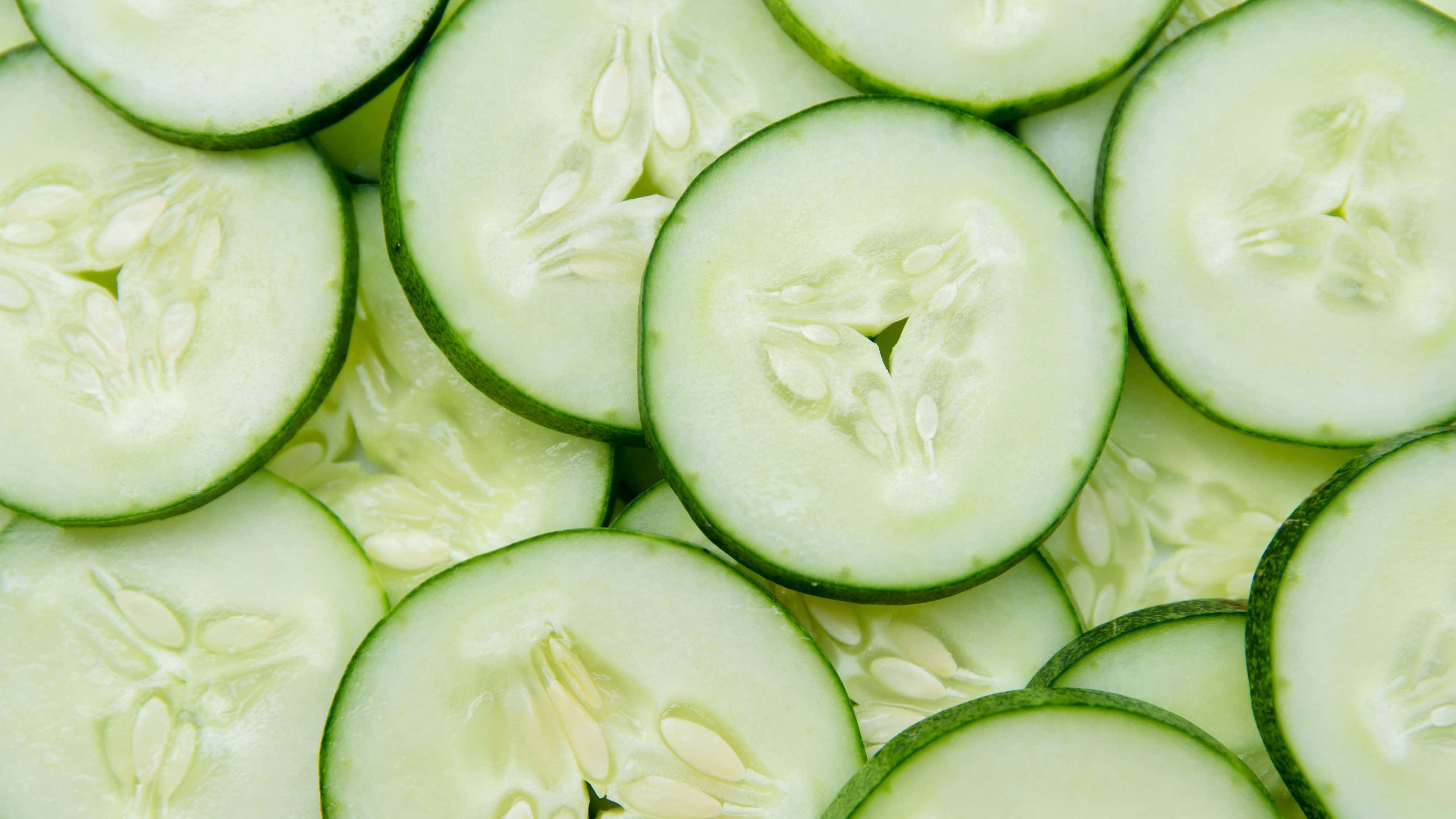 cucumber 桌布 壁紙 — 新鮮黃瓜片排列成充滿活力的綠色圖案，展示其爽脆質地和淡色種子。