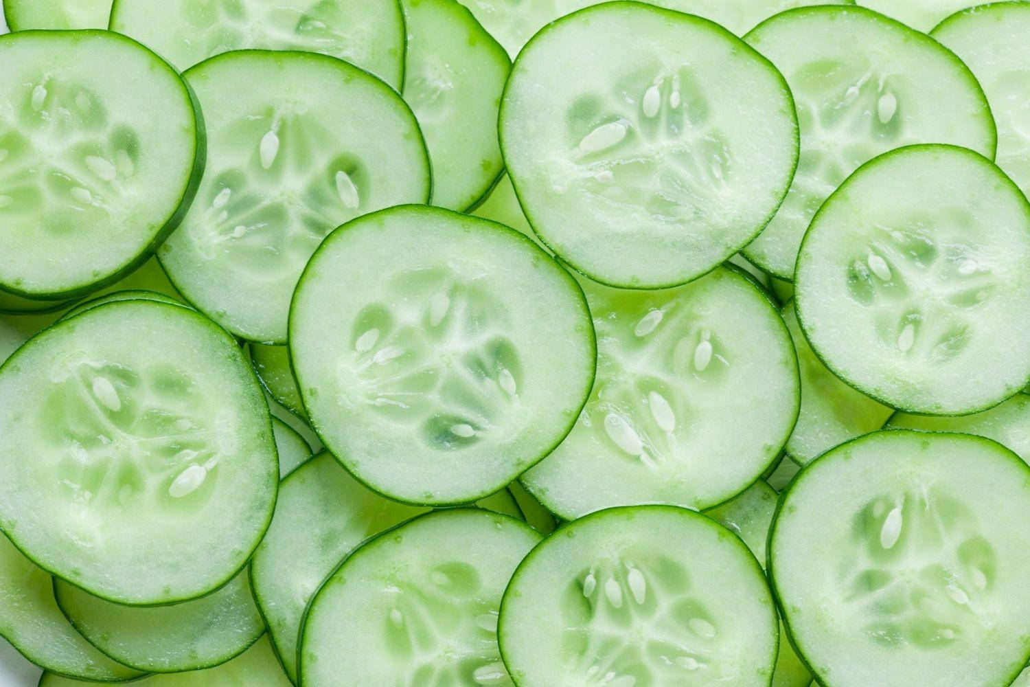 sliced 桌布 壁紙 — 新鮮黃瓜片排列成充滿活力的綠色圖案，展示其爽脆質地和籽室。
