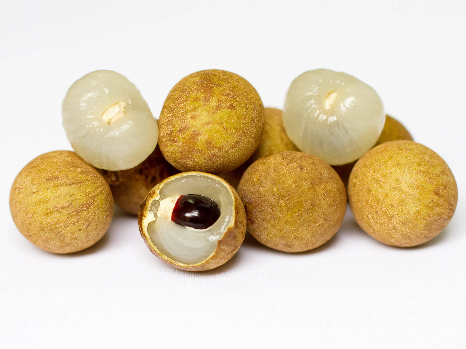 Fruits 桌布 壁紙 — 新鮮龍眼果實，帶有半透明白色果肉和深色種子，聚集在潔白背景上。