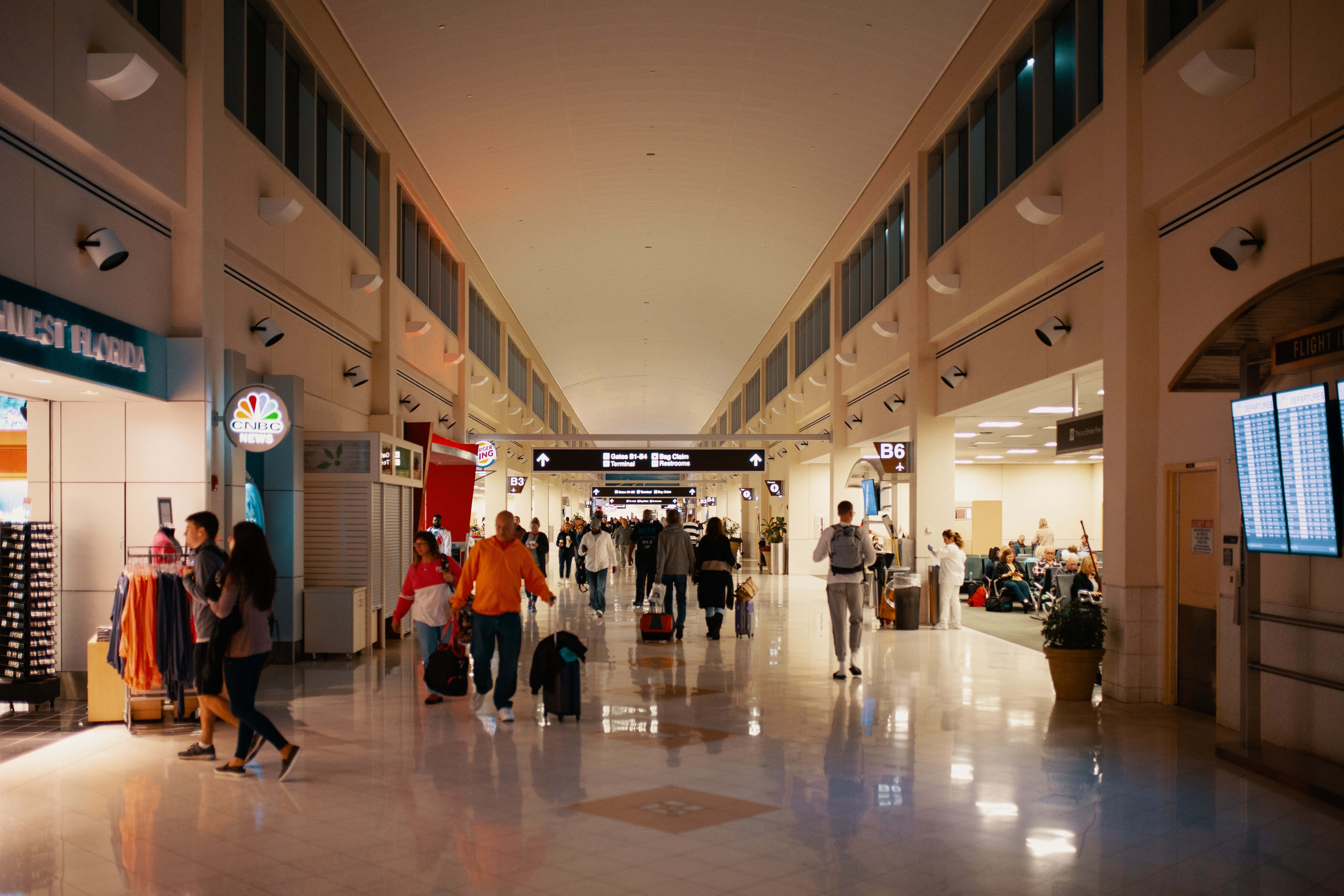Airport 桌布 壁紙 — 旅客在光線明亮的機場航廈中穿梭，拋光地板和頭頂標誌引導他們穿過繁忙的空間。