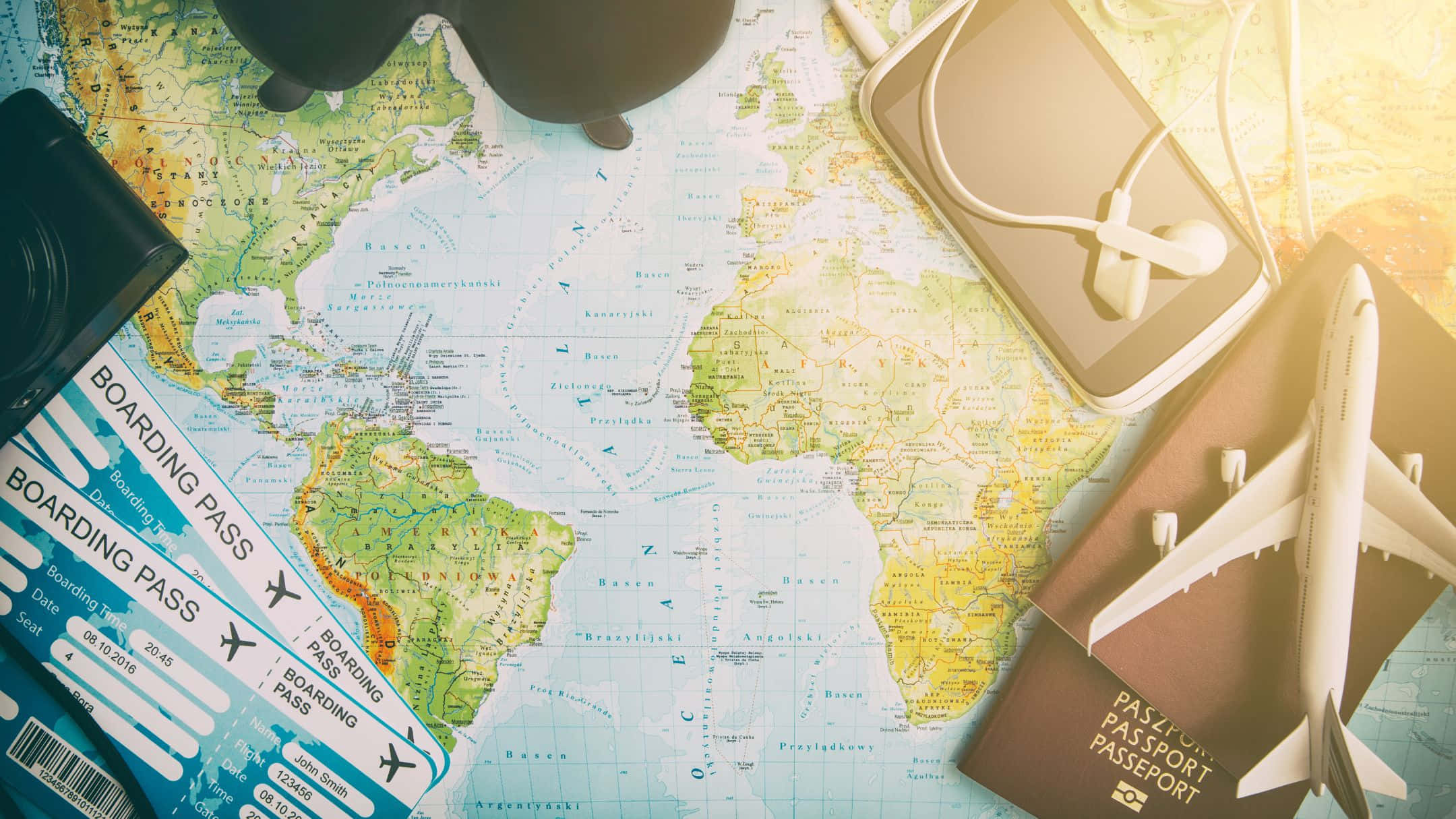 Map 桌布 壁紙 — 旅行裝備包括登機證、護照和玩具飛機，排列在世界地圖上，伴隨著溫暖的陽光。