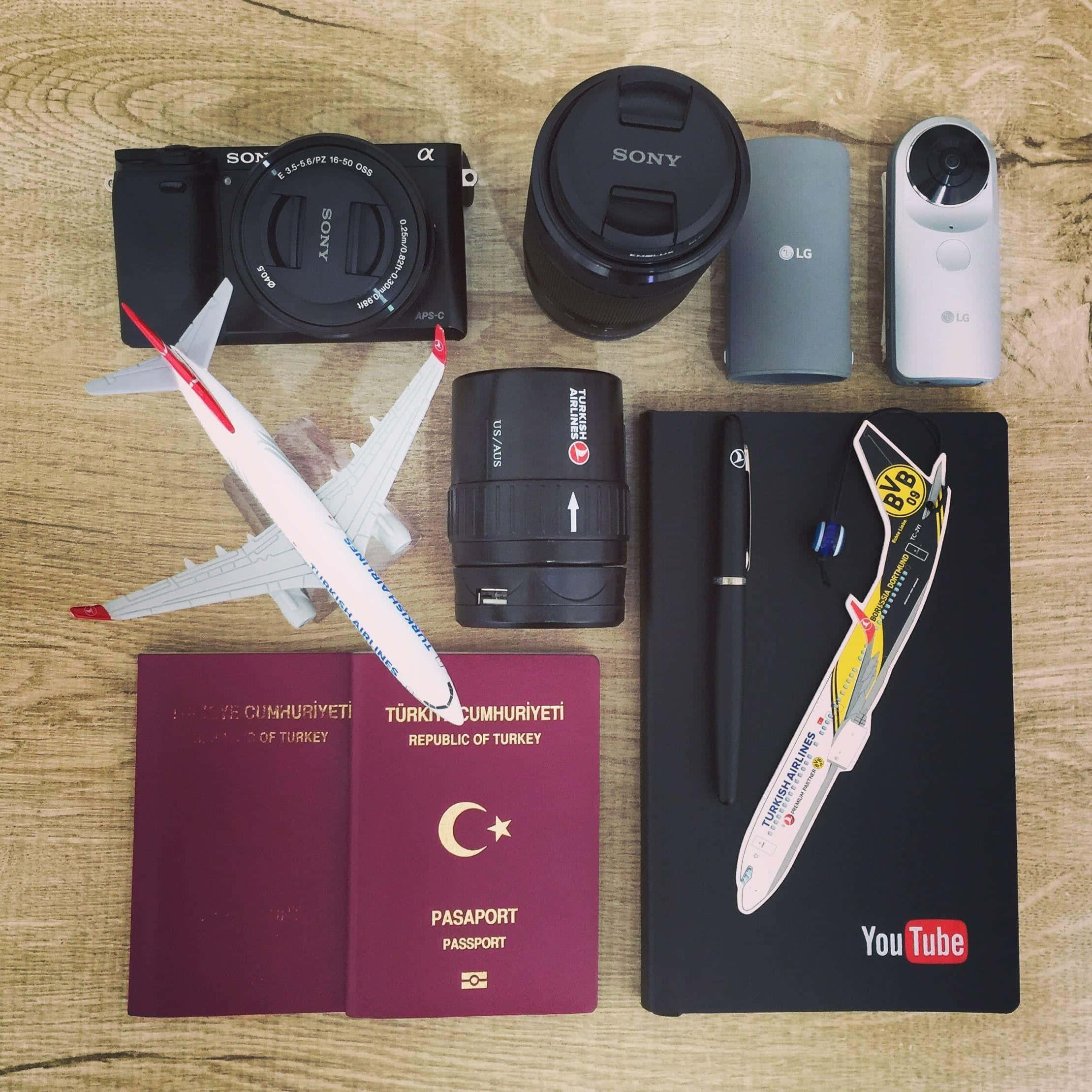 Passport 桌布 壁紙 — 旅行裝備的平鋪擺放，包括土耳其護照、相機鏡頭和一本YouTube品牌的筆記本，置於木頭上。