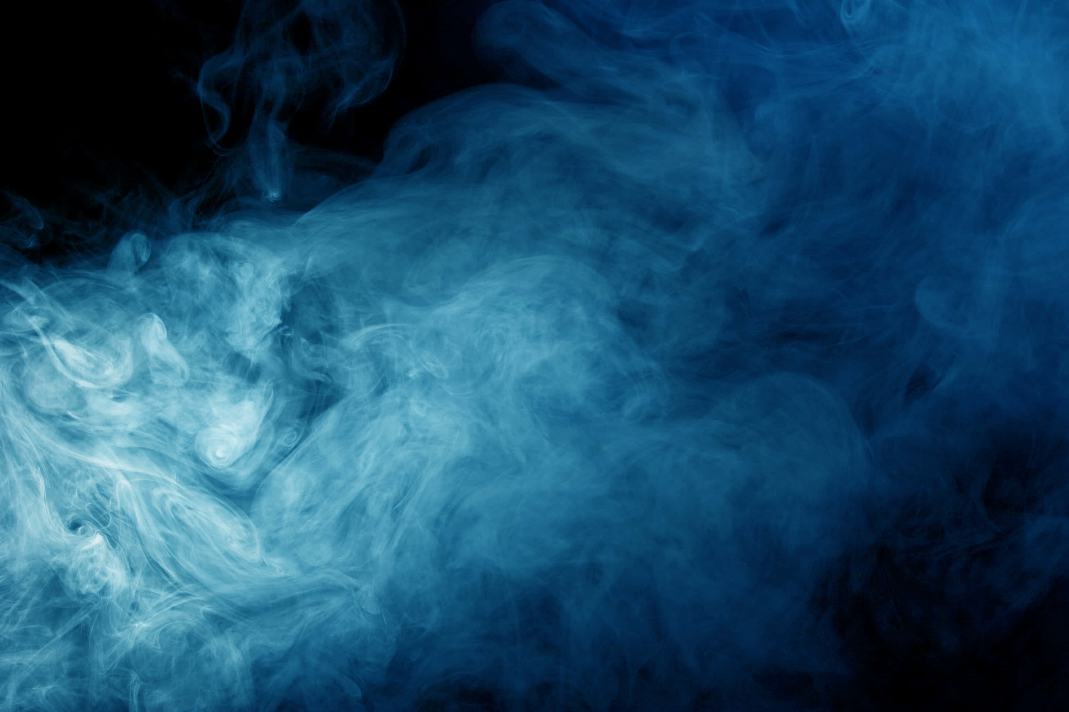 Smoke Blue 桌布 壁紙 — 旋轉的藍色煙霧在純黑背景上飄移，營造出空靈神秘的氛圍。