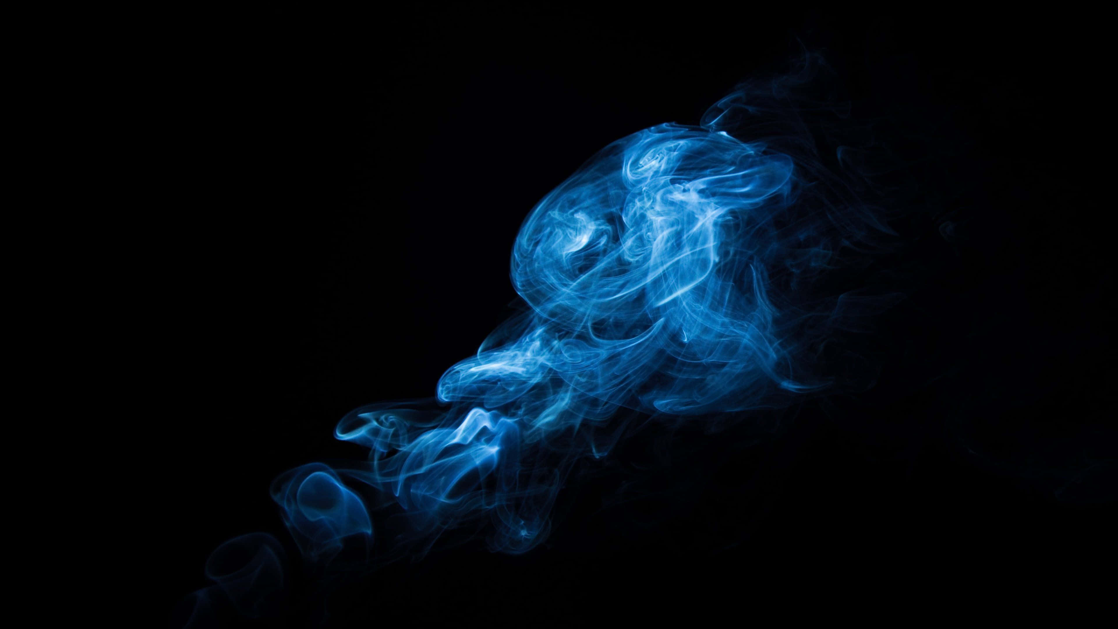 桌布 壁紙 — 旋轉的藍色煙霧在純黑色背景上發光，營造出空靈而神秘的氛圍。