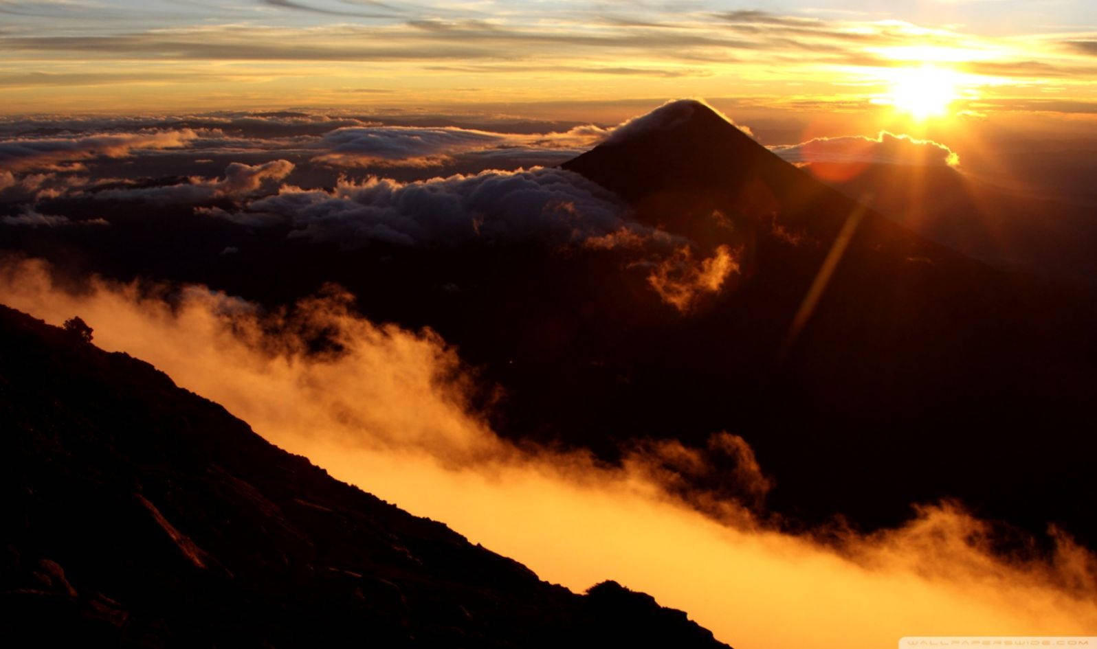 Guatemala 桌布 壁紙 — 日出在雲海之上為山峰塗上金色光芒。