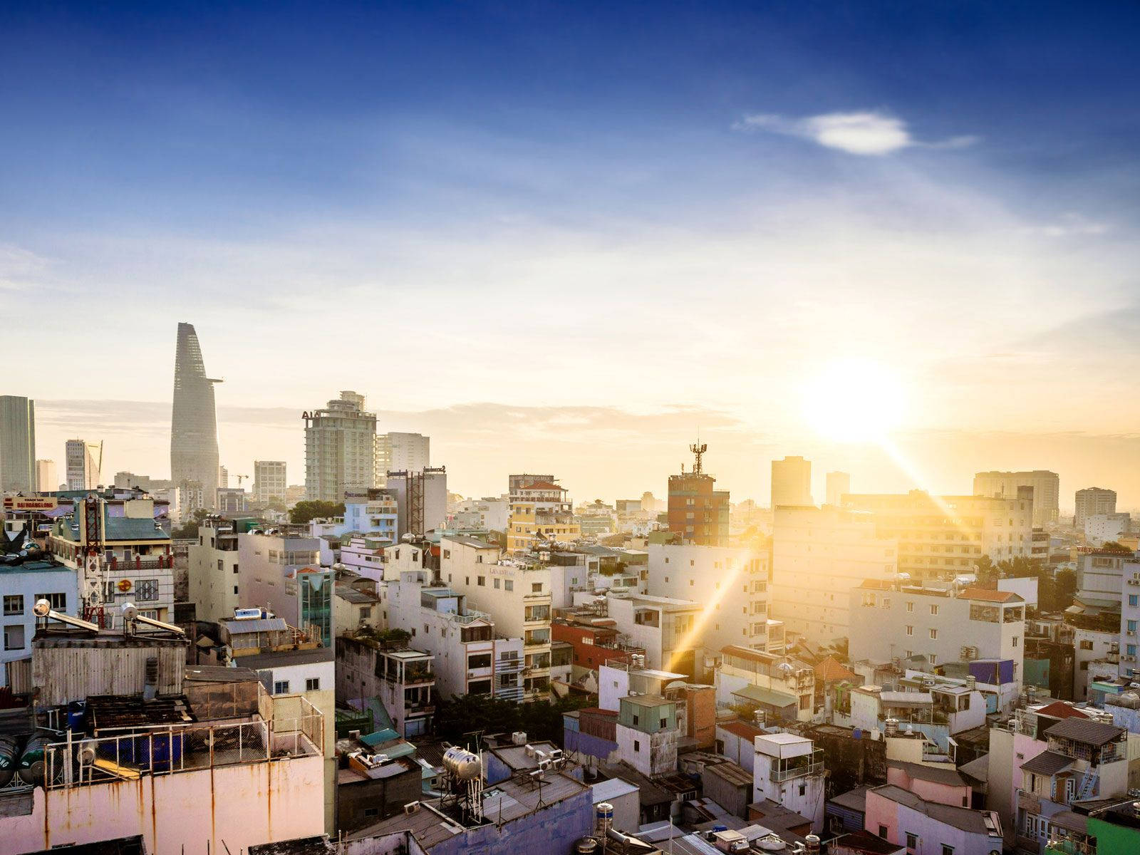 Ho Chi Minh City 桌布 壁紙 — 日出將密集的城市天際線沐浴在金色光芒中，現代塔樓聳立在密密麻麻的住宅建築之上。