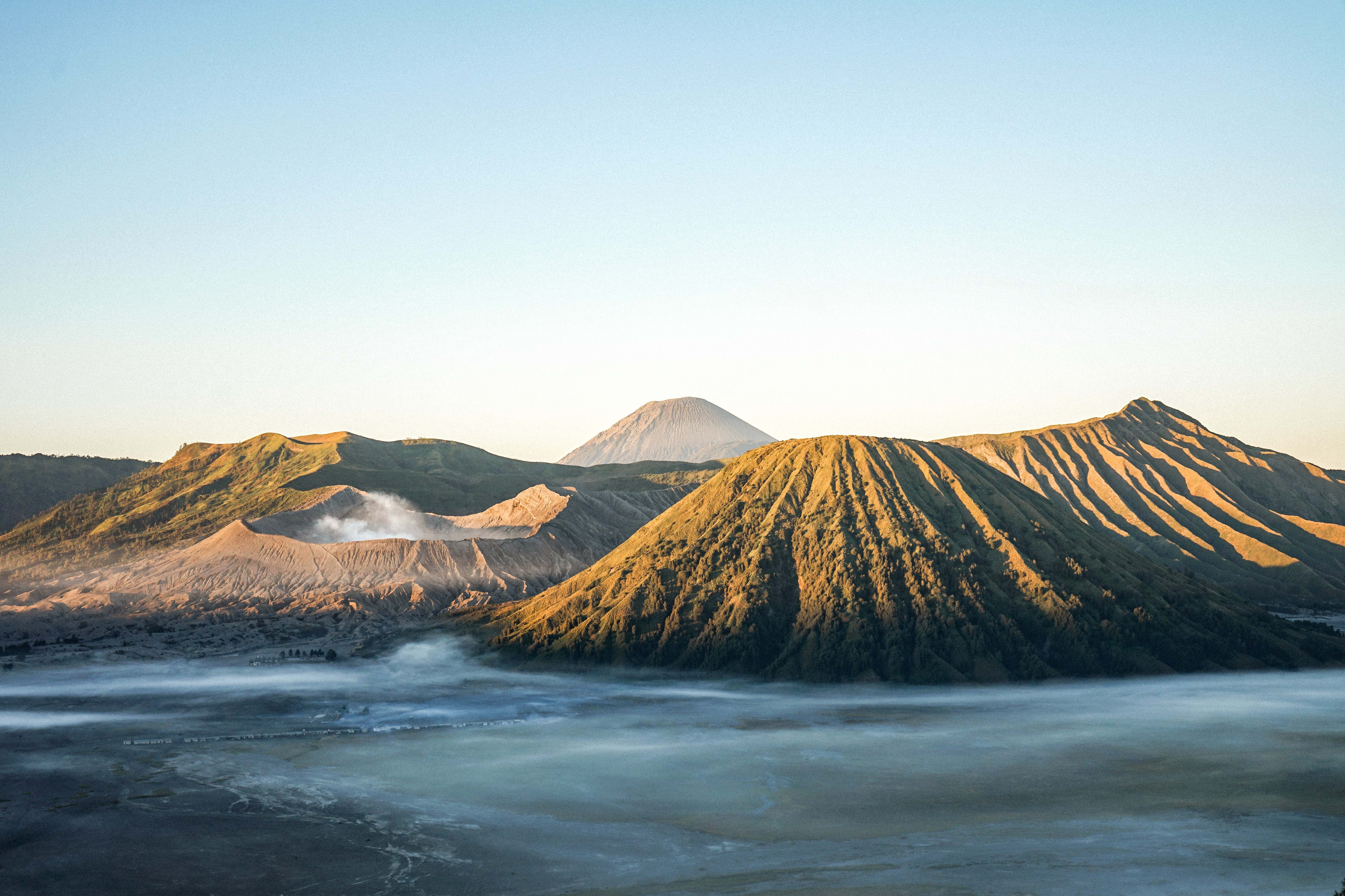 photo 桌布 壁紙 — 日出將火山山脈沐浴在金色光芒中，薄霧在山谷中翻滾。