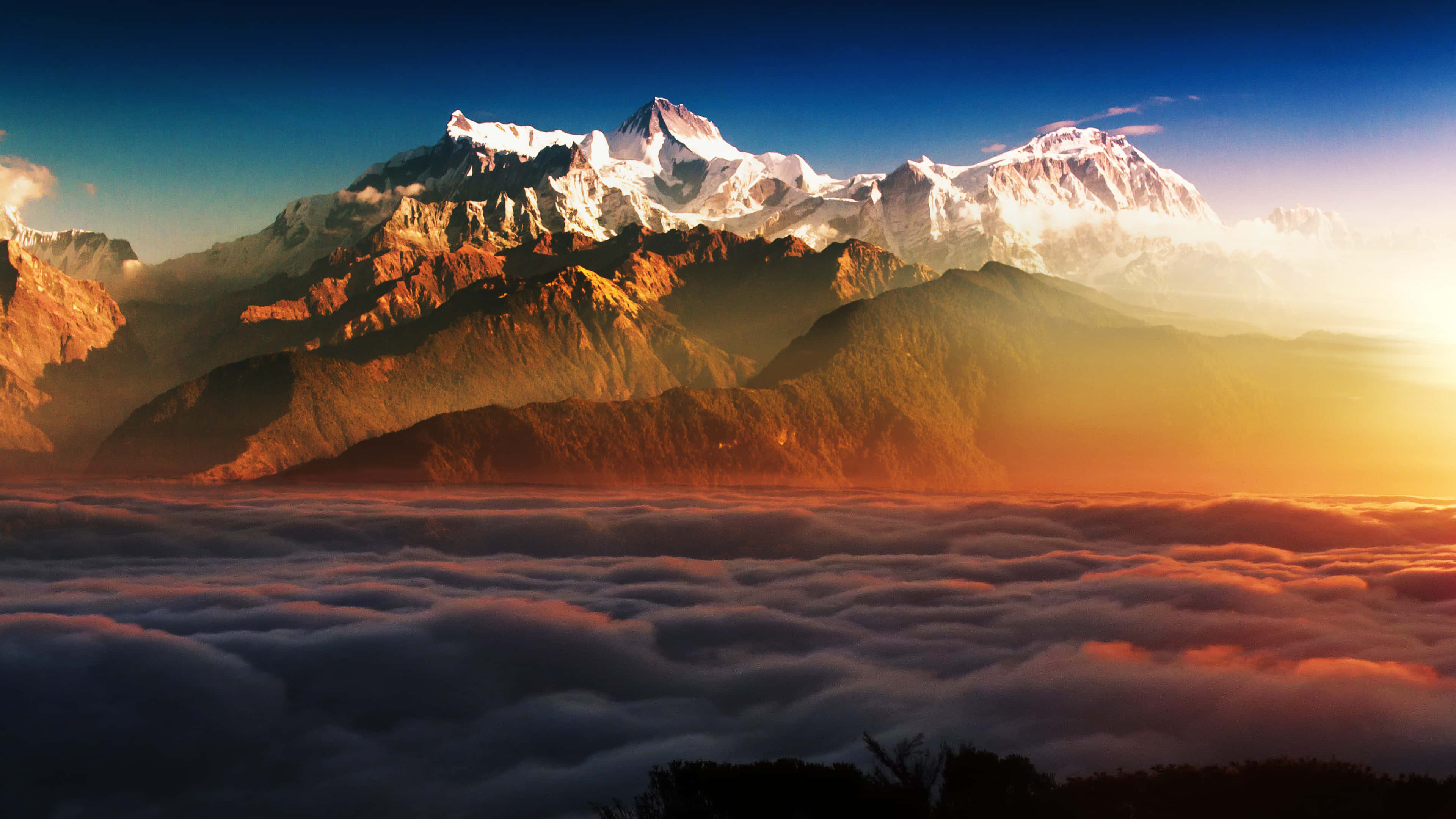 Clouds 4K 桌布 壁紙 — 日出將積雪的山峰沐浴在雲海之上的金色光芒中。