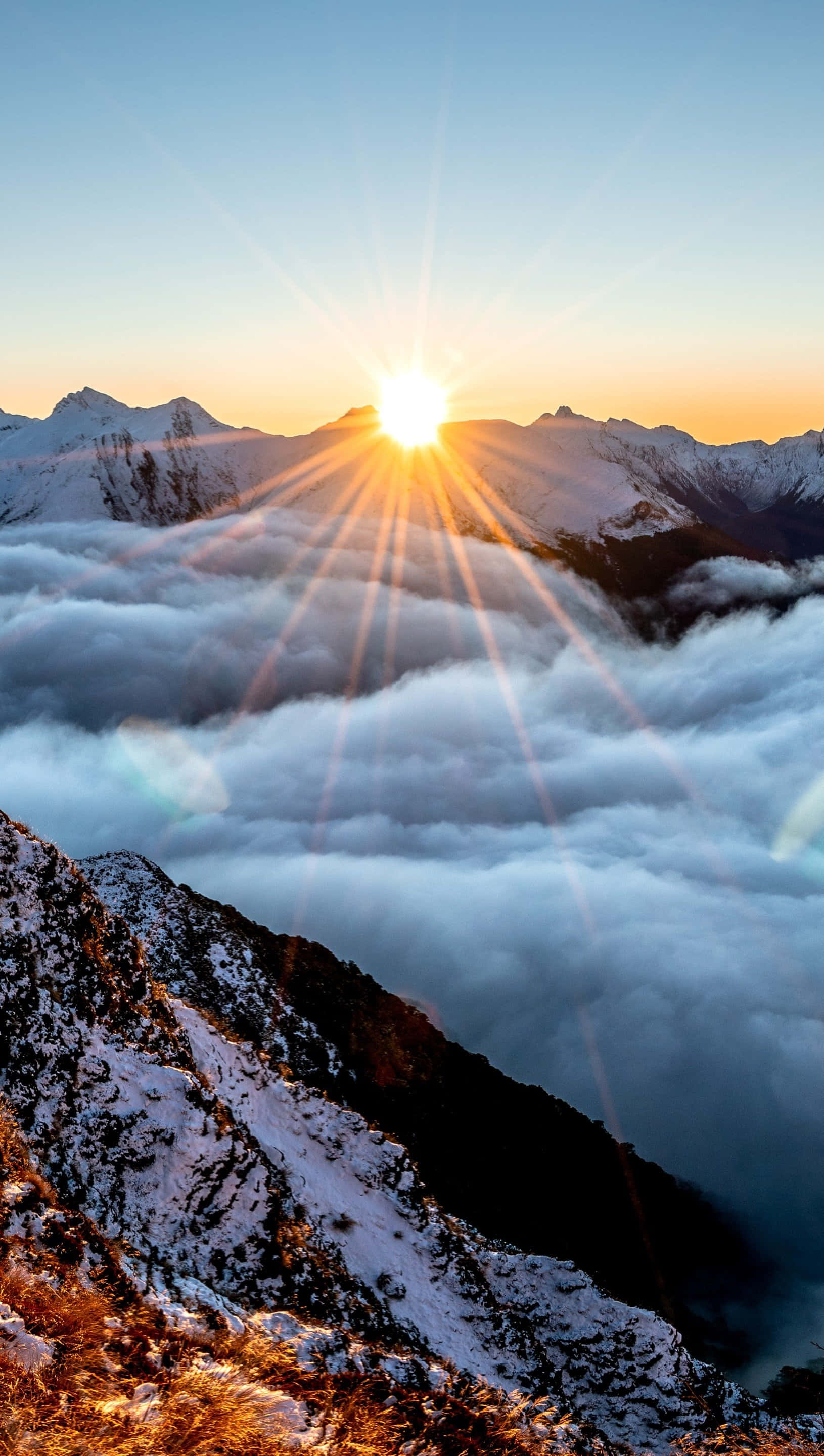 雲朵 桌布 壁紙 — 日出時，陽光穿透雲海之上白雪覆蓋的山峰。