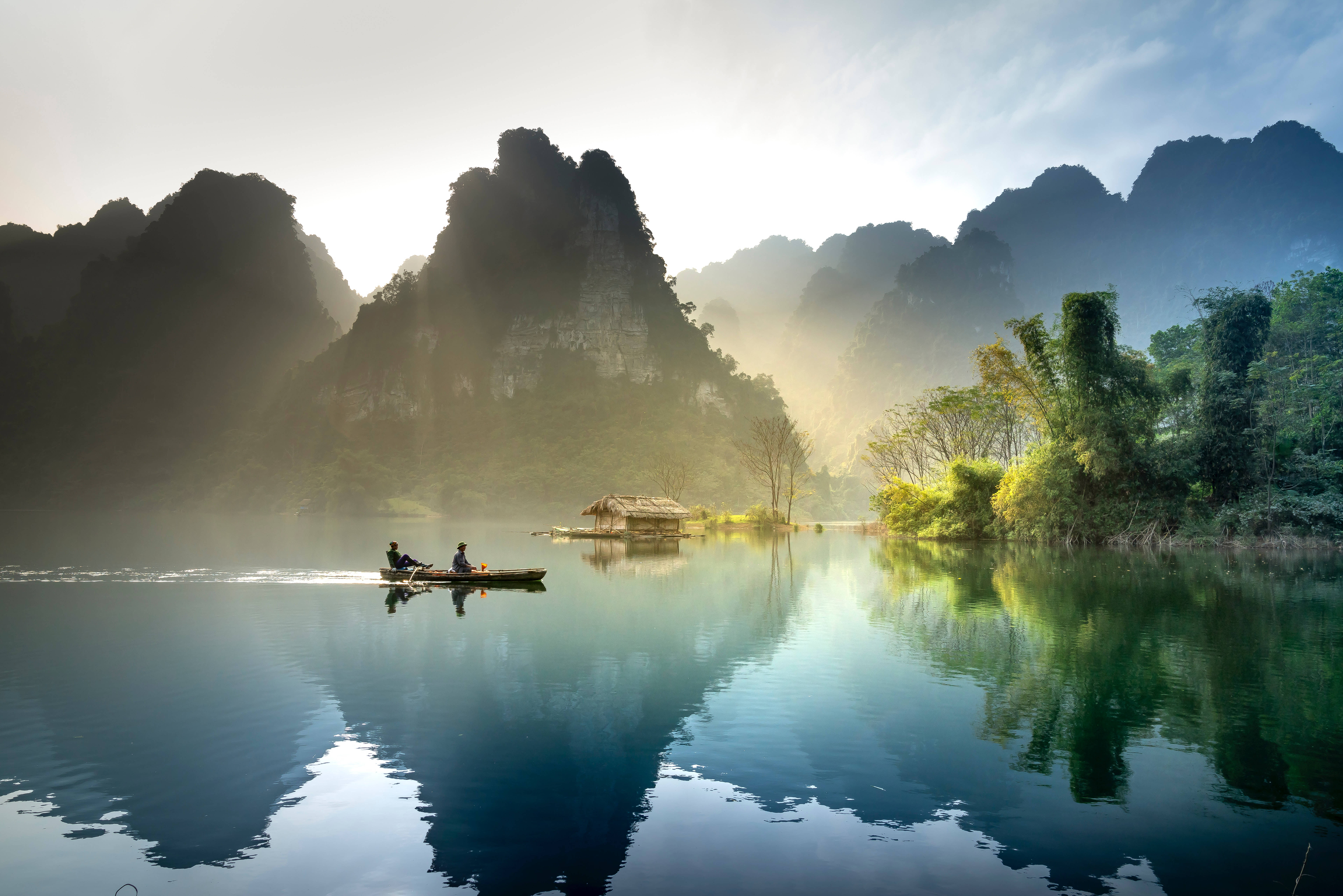 river 桌布 壁紙 — 日出時分，兩人在霧氣瀰漫的湖上划船，四周是高聳的喀斯特山峰。