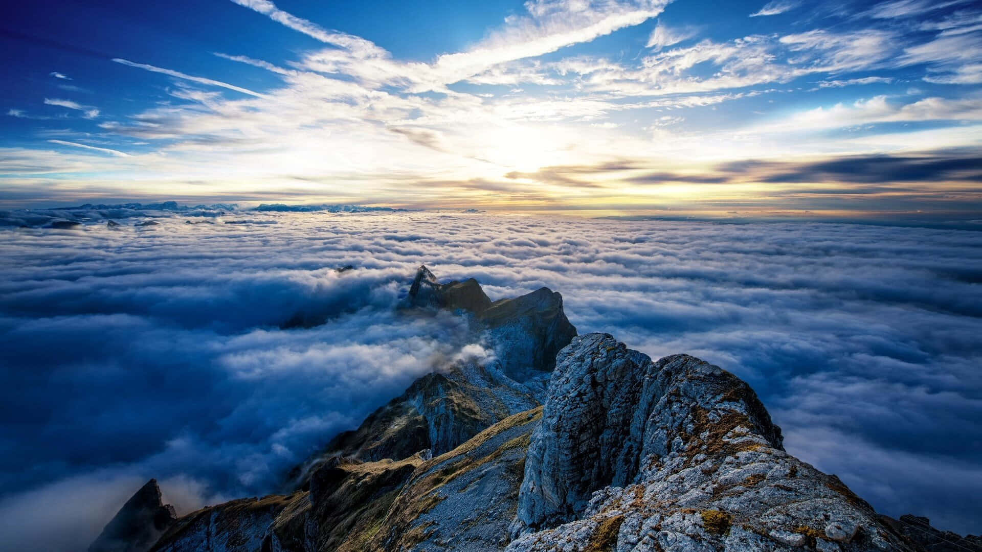 雲朵 桌布 壁紙 — 日出時分，戲劇性的山峰從雲海中升起，伴隨著鮮豔的藍天和金色的光芒。