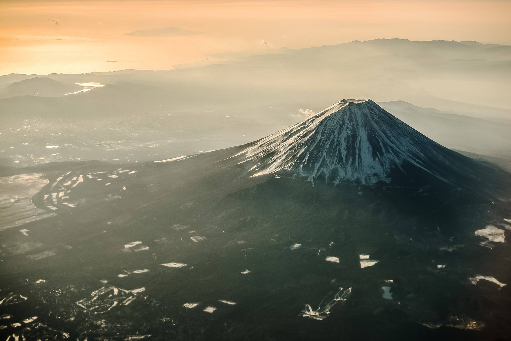 富士山 桌布 壁紙 — 日出時分，白雪覆蓋的富士山鳥瞰圖，金色光芒照亮山頂和下方霧氣繚繞的山谷。