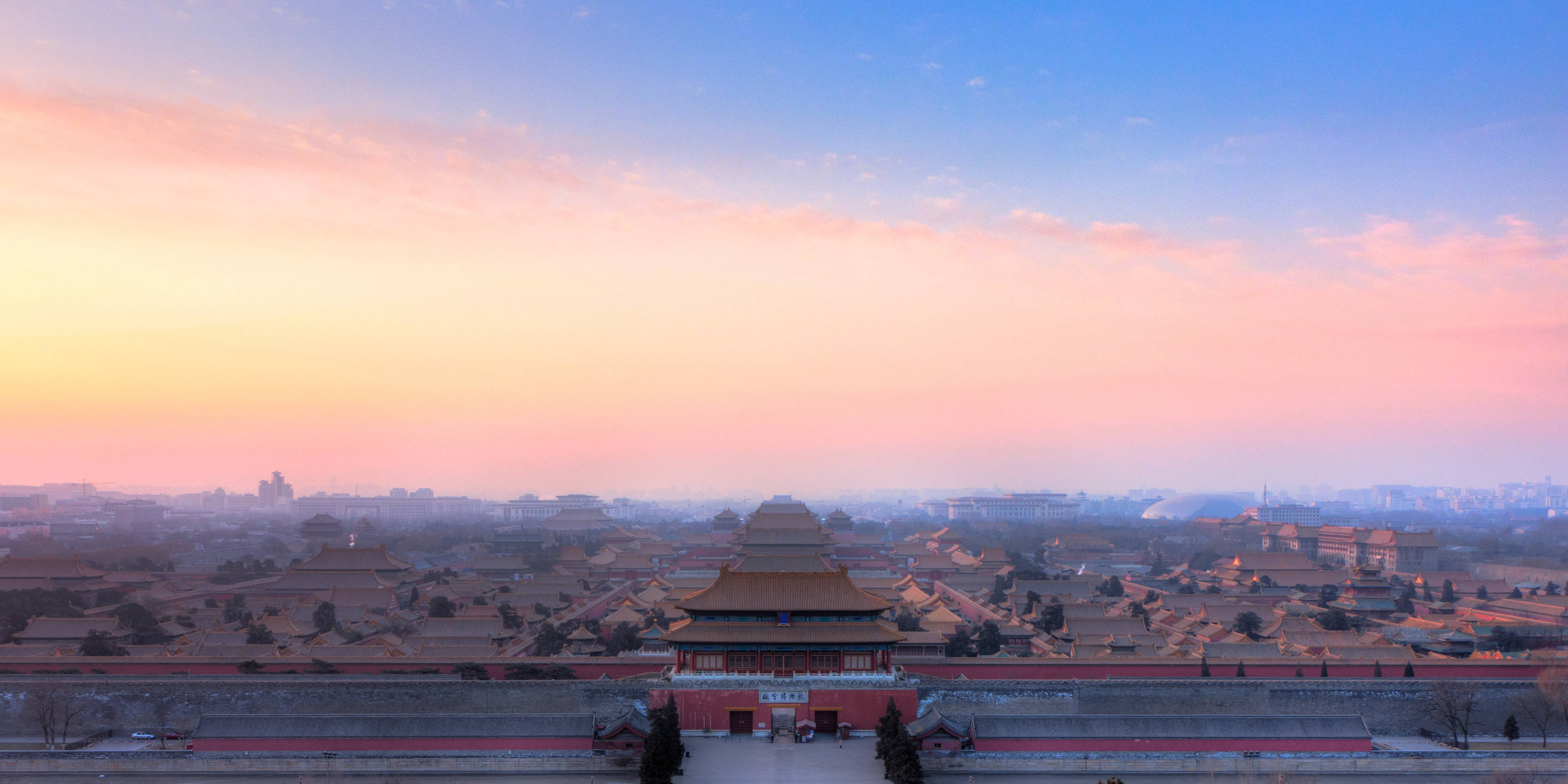 中國 桌布 壁紙 — 日出時分紫禁城的全景，粉紅色和橙色的天空在傳統的紅色和金色屋頂之上。
