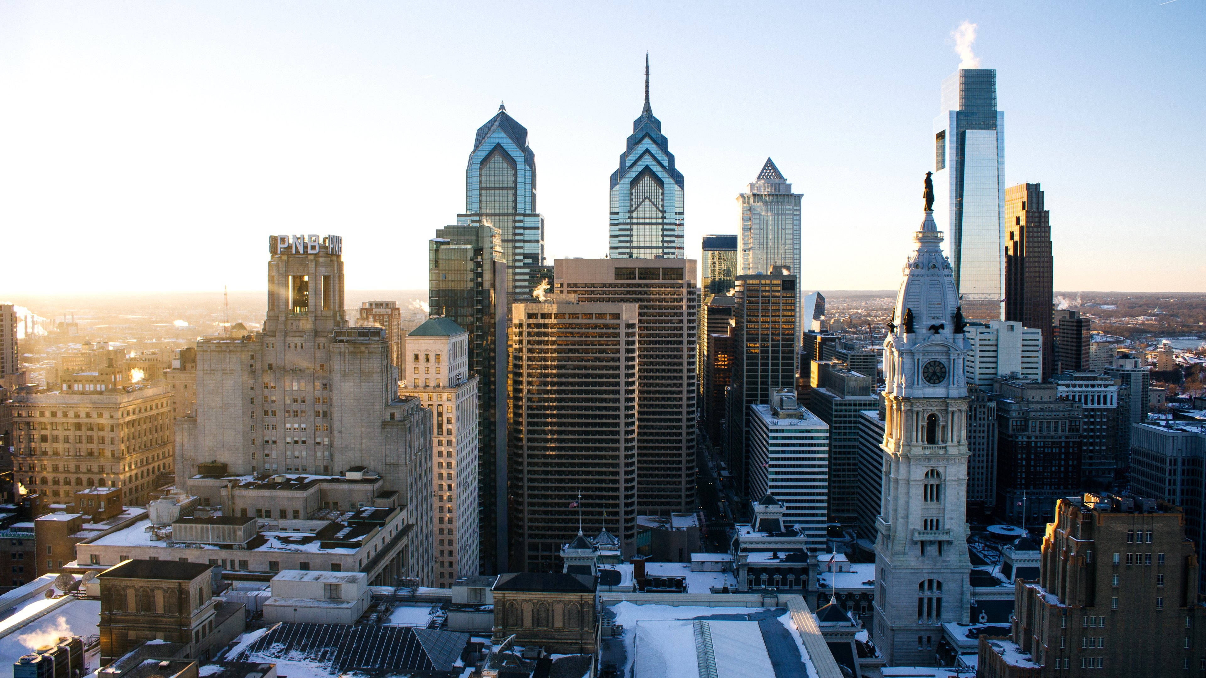 Philadelphia 桌布 壁紙 — 日出照耀著積雪的費城天際線，歷史悠久的鐘樓和現代玻璃摩天大樓。