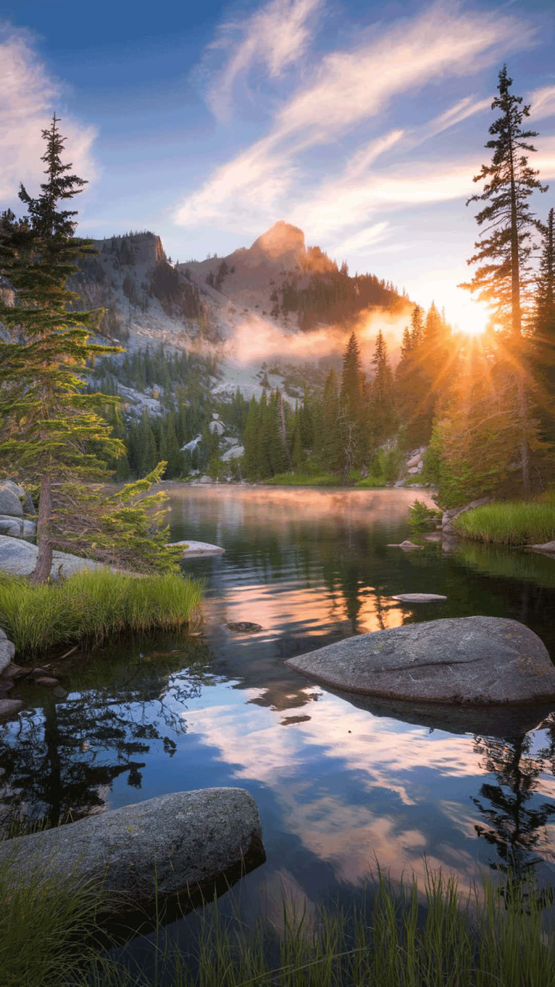 Serene mountain lake at sunrise  nature wallpaper 壁紙 — 日出穿過松樹，將金色光芒投射在霧氣繚繞的山巒上，倒映在寧靜的高山湖泊中。