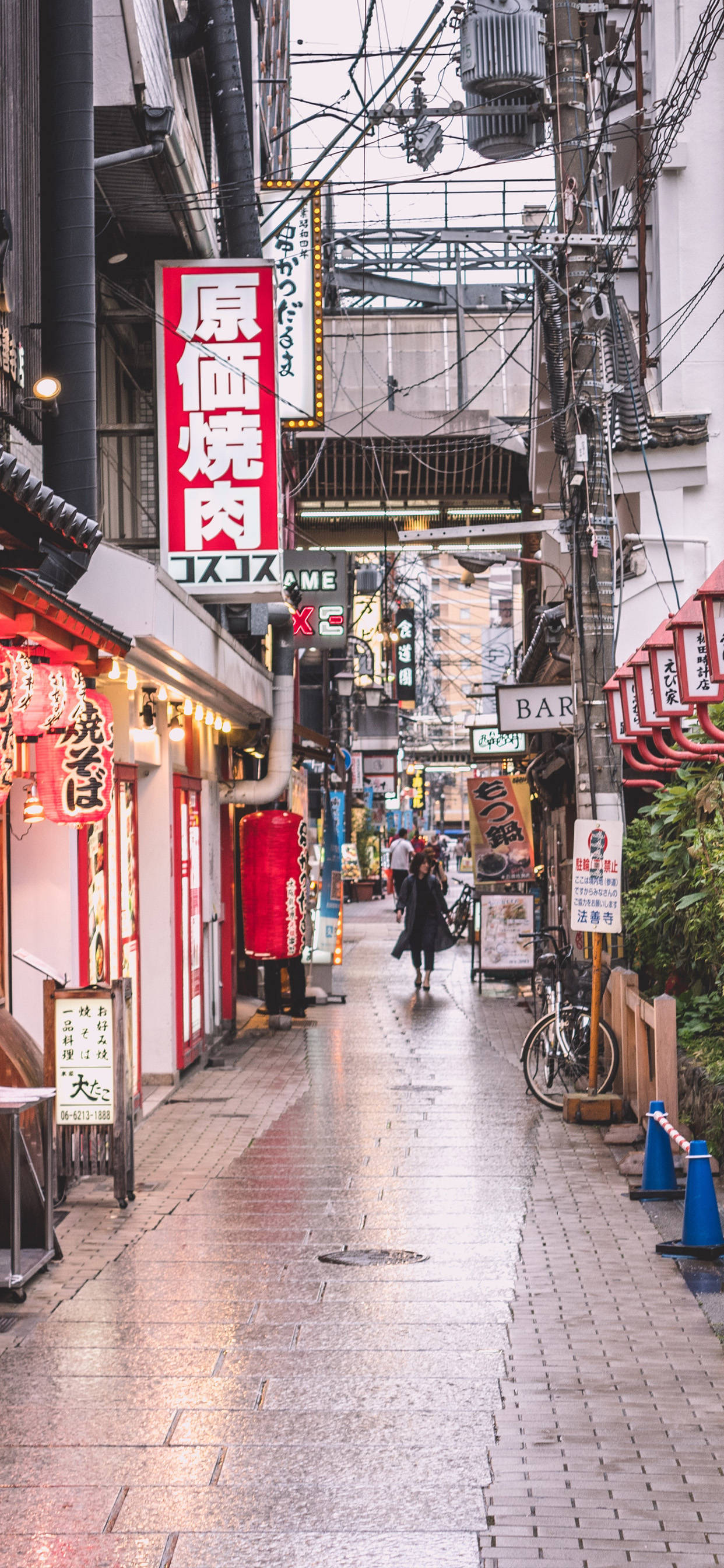 日本 桌布 壁紙 — 日本一條雨中的小巷，兩旁是發光的霓虹燈招牌和傳統木製店面，倒映在濕漉漉的路面上。