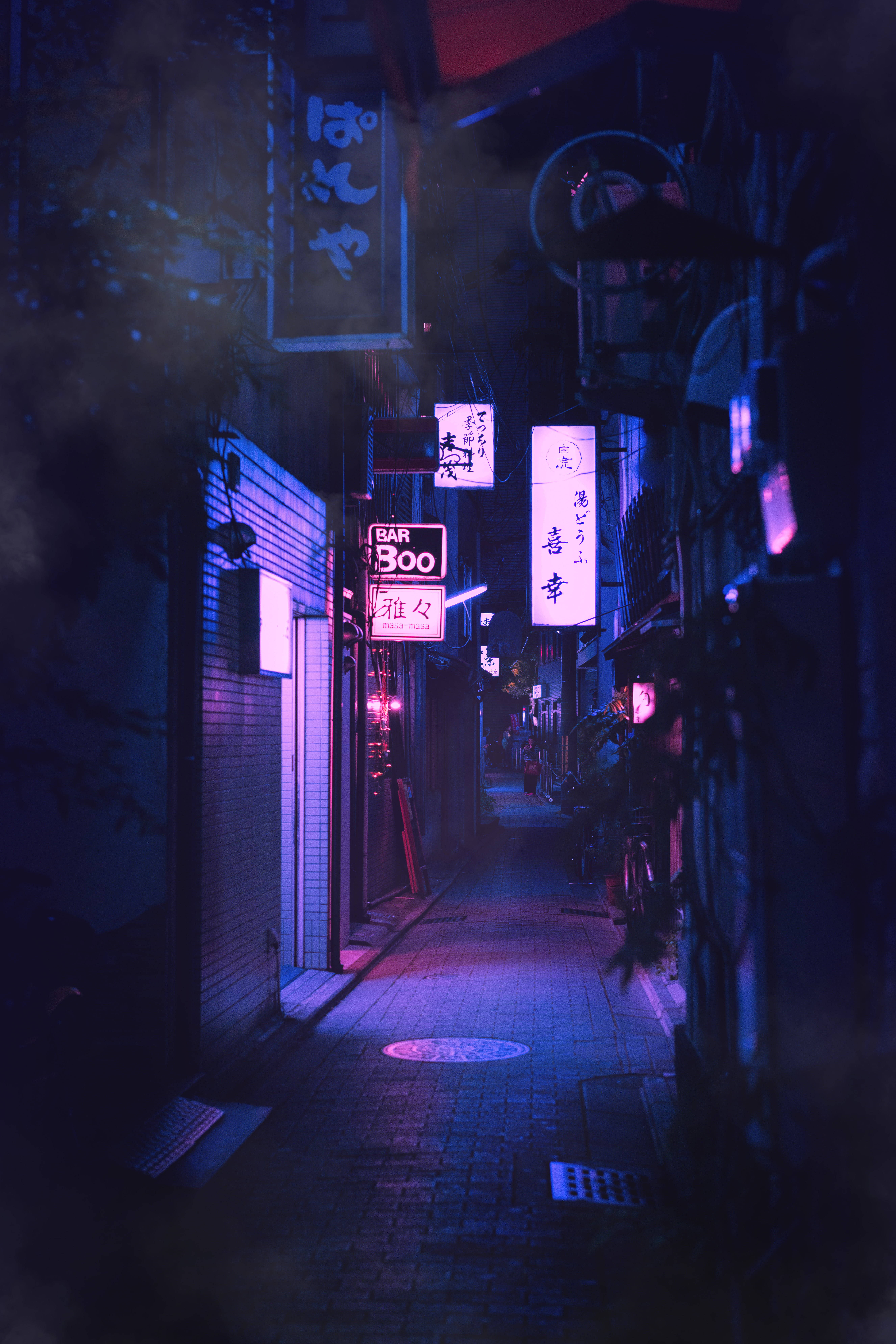 霓虹美學 桌布 壁紙 — 日本城市夜晚一條狹窄的霓虹燈小巷，發光的招牌在潮濕的路面上投射出紫色和藍色的色調。