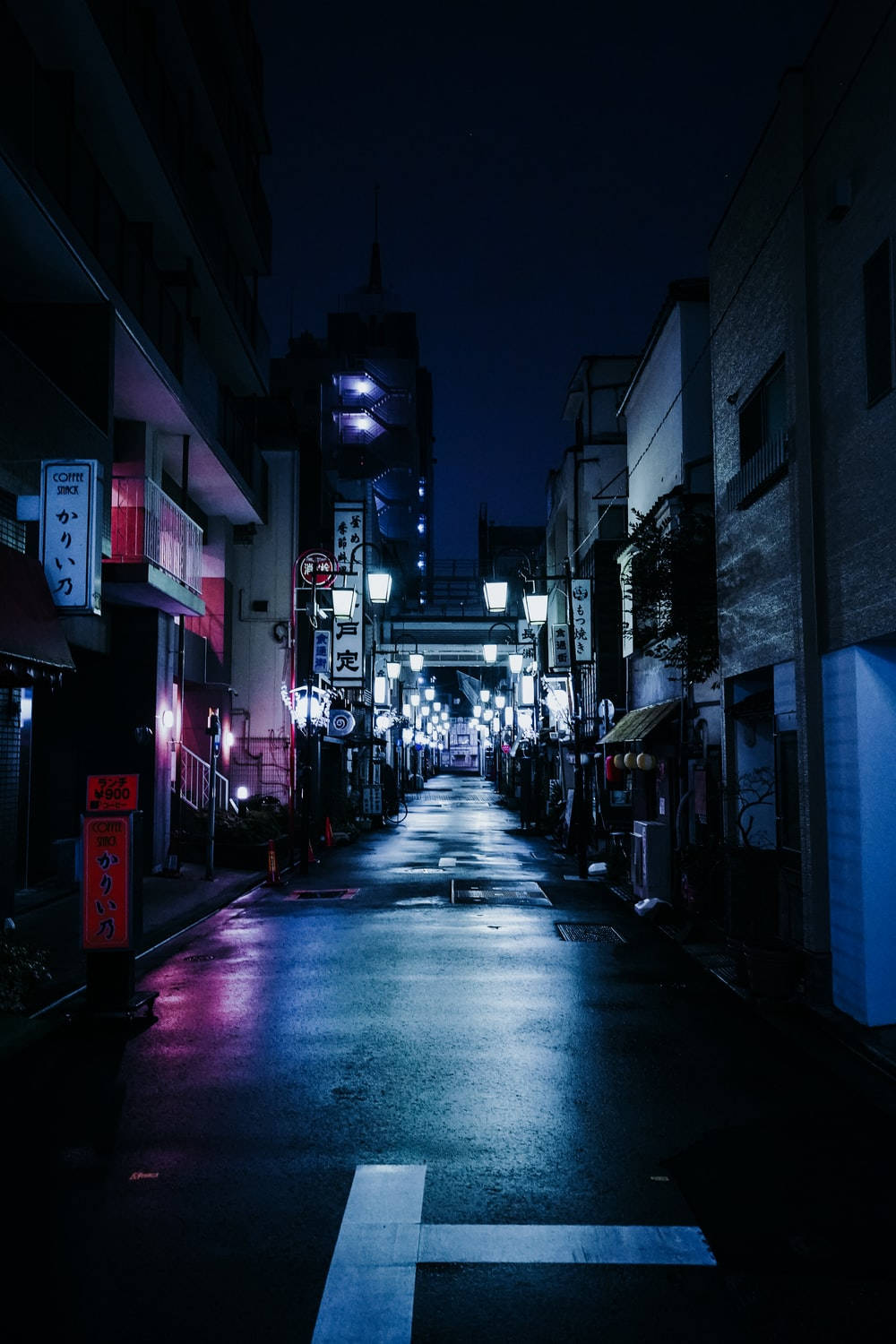 Dark Night 桌布 壁紙 — 日本夜晚一條狹窄潮濕的小巷，被發光的霓虹燈招牌和街燈照亮，在路面上投下倒影。