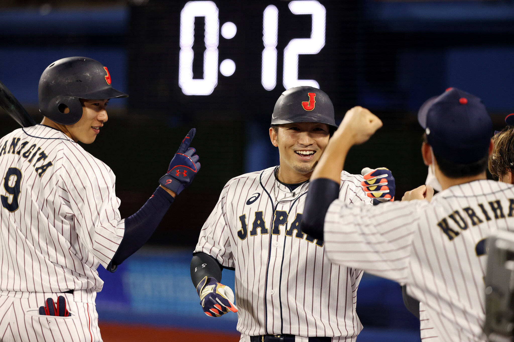 運動 桌布 壁紙 — 日本棒球運動員穿著細條紋制服，在體育場燈光下擊掌慶祝勝利。