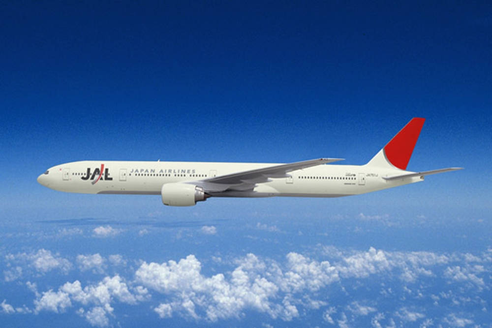 雲朵 桌布 壁紙 — 日本航空客機在深藍色天空襯托下，優雅地翱翔於蓬鬆白雲之上。