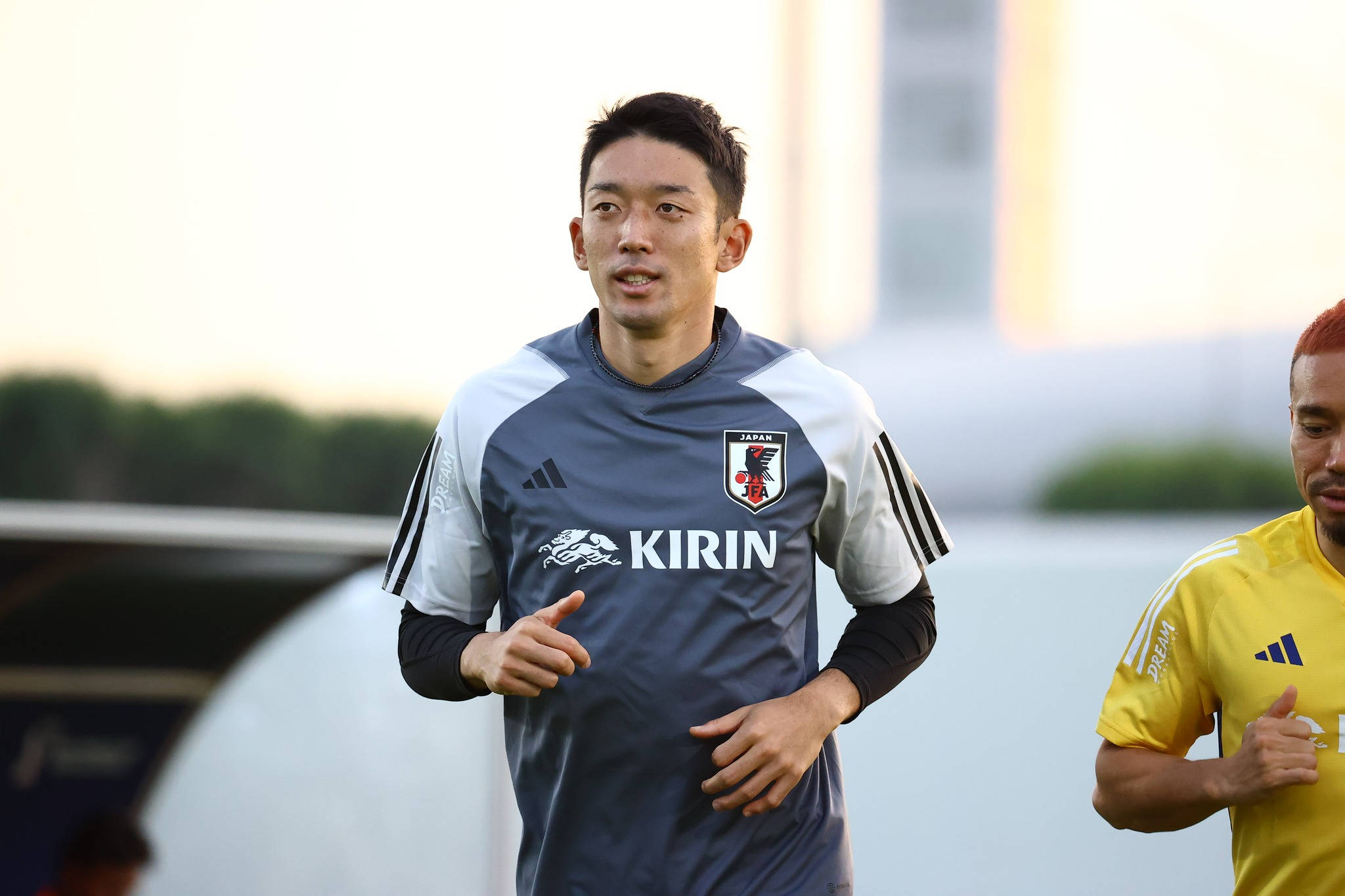 Football Players 桌布 壁紙 — 日本足球運動員身穿藍色訓練服，在傍晚訓練期間與隊友在體育場附近慢跑。