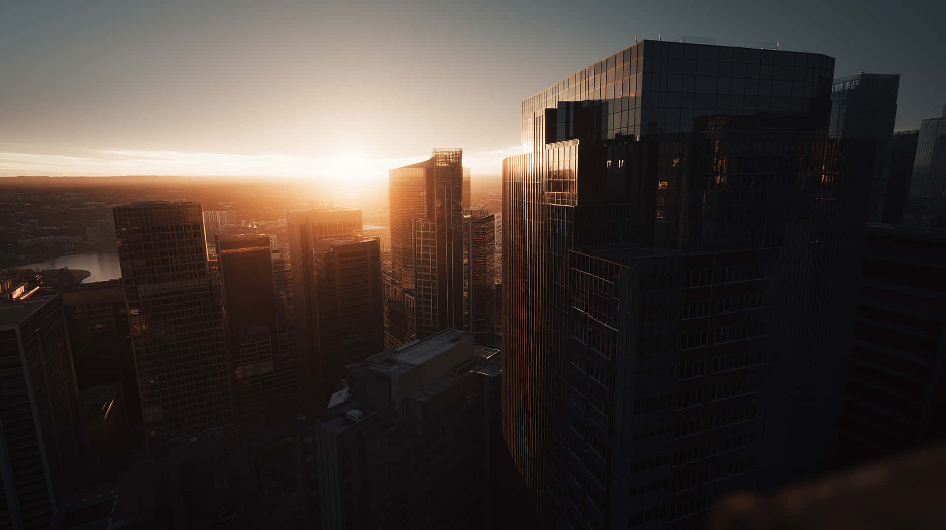 City Buildings Silhouette Against Glowing Horizon 壁紙 — 日落於摩天大樓後方發光，將金色光線投射在密集城市天際線的玻璃外牆上。