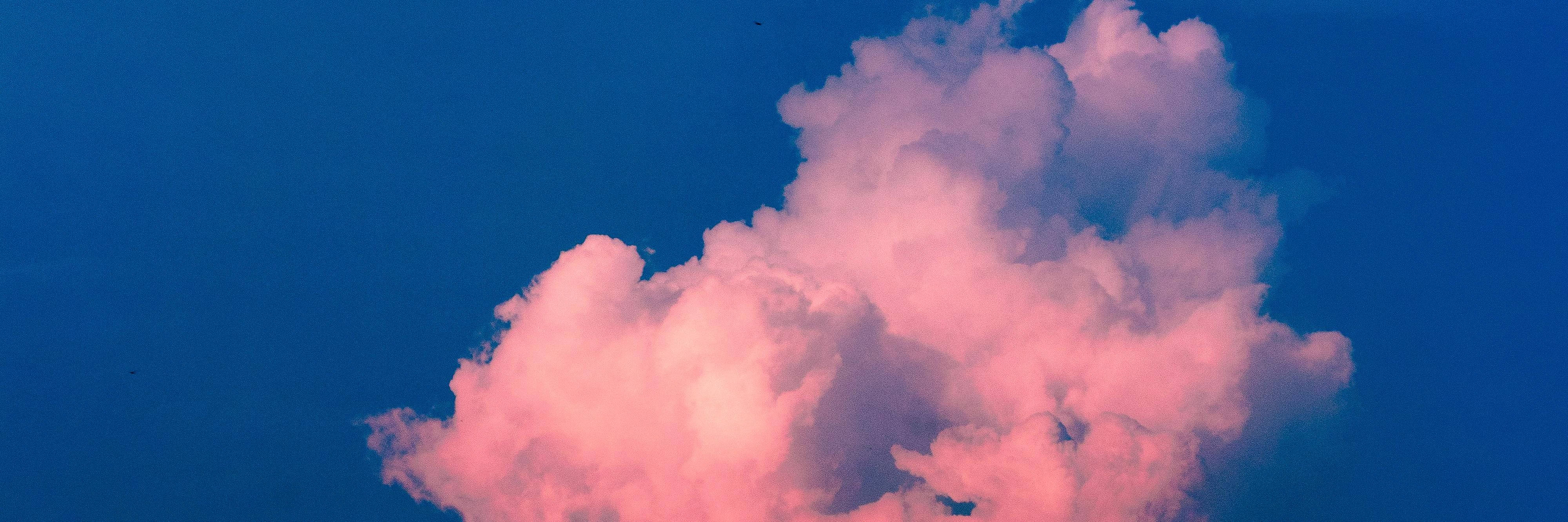 夜空 桌布 壁紙 — 日落時分，一朵蓬鬆的雲在深藍色的天空中閃耀著粉紅色的光芒。