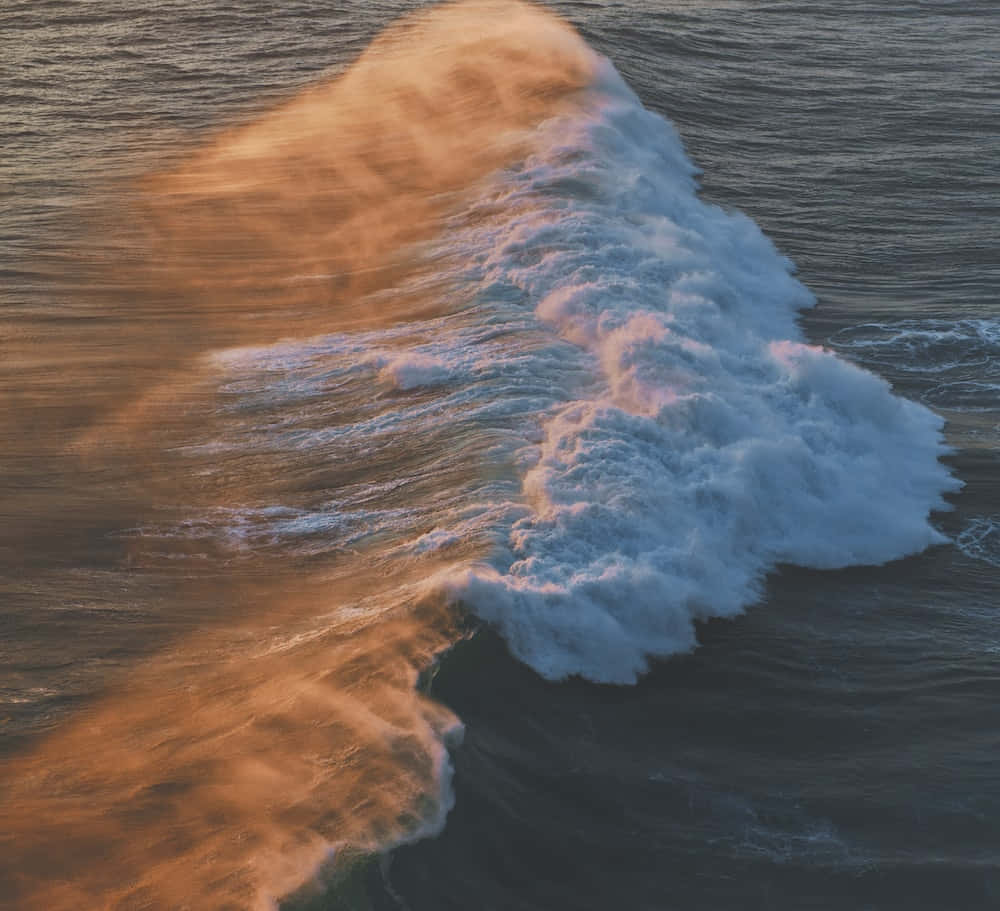 Wave 桌布 壁紙 — 日落時分，強勁的海浪在深藍色海面上翻湧，泛起金色水花的空拍視角。