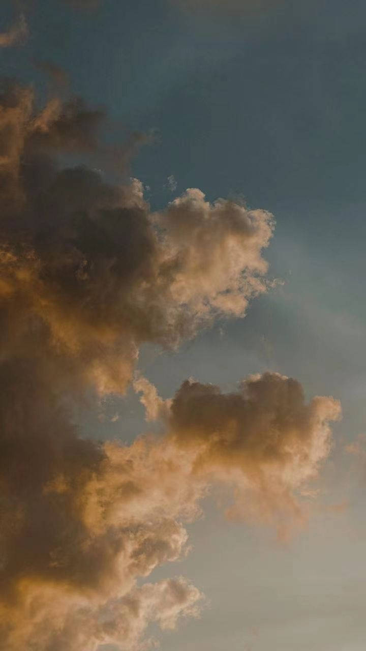 雲朵 桌布 壁紙 — 日落時分，深藍綠色天空映襯下，戲劇性的雲朵閃耀著琥珀色和金色光芒。